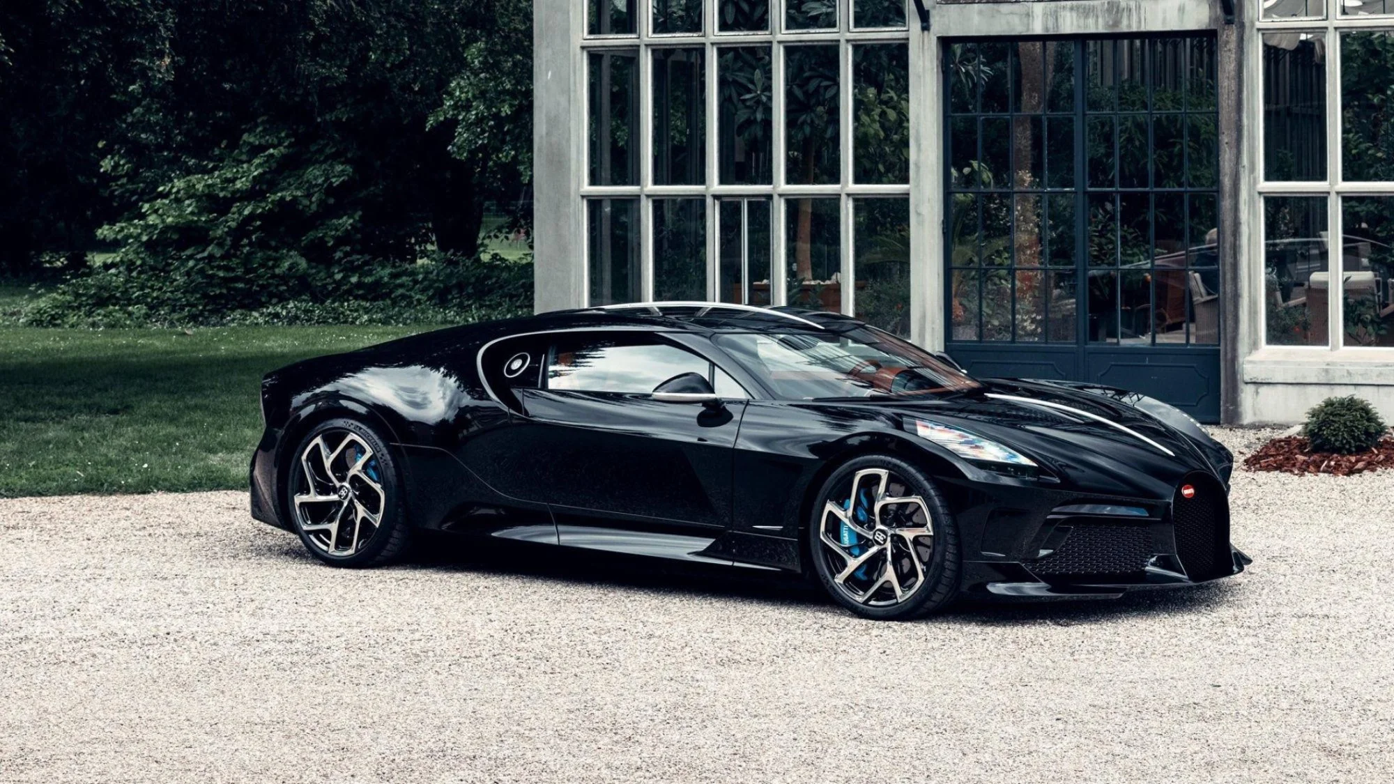 Black Bugatti supercar parked in front of a grand home, illustrating the kind of collection Motor Volta car condominiums are built for