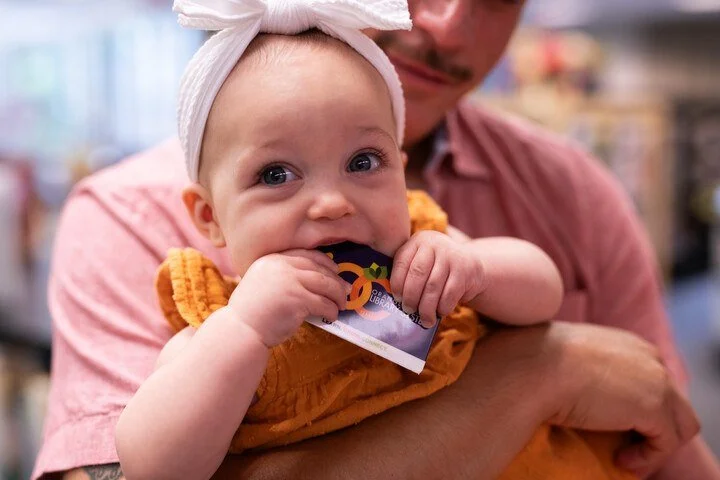 Baby holding an Orange County Library System library card