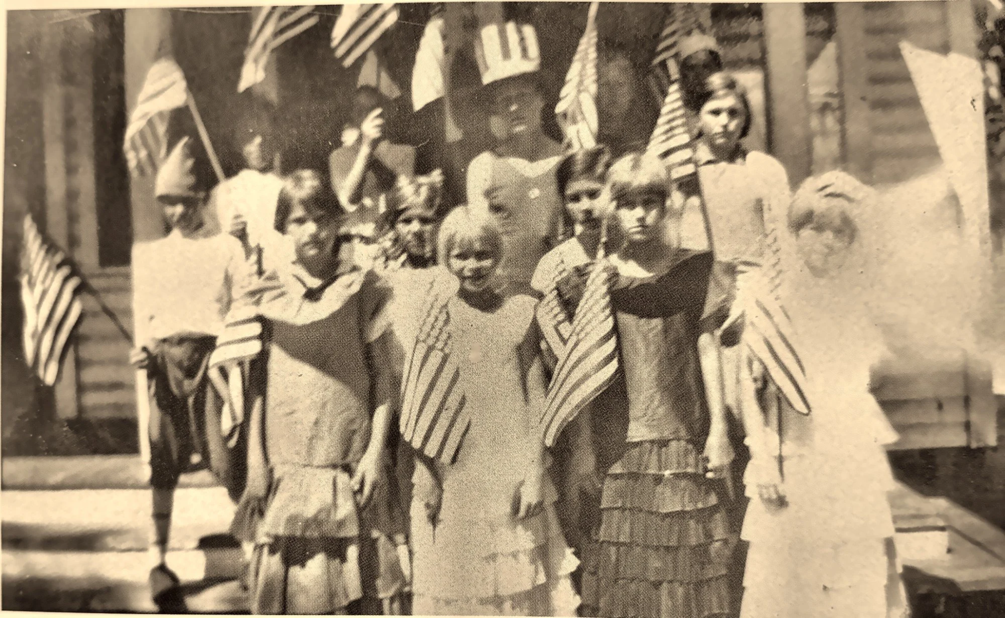 Historic sepia photo of a crowd waving American flags