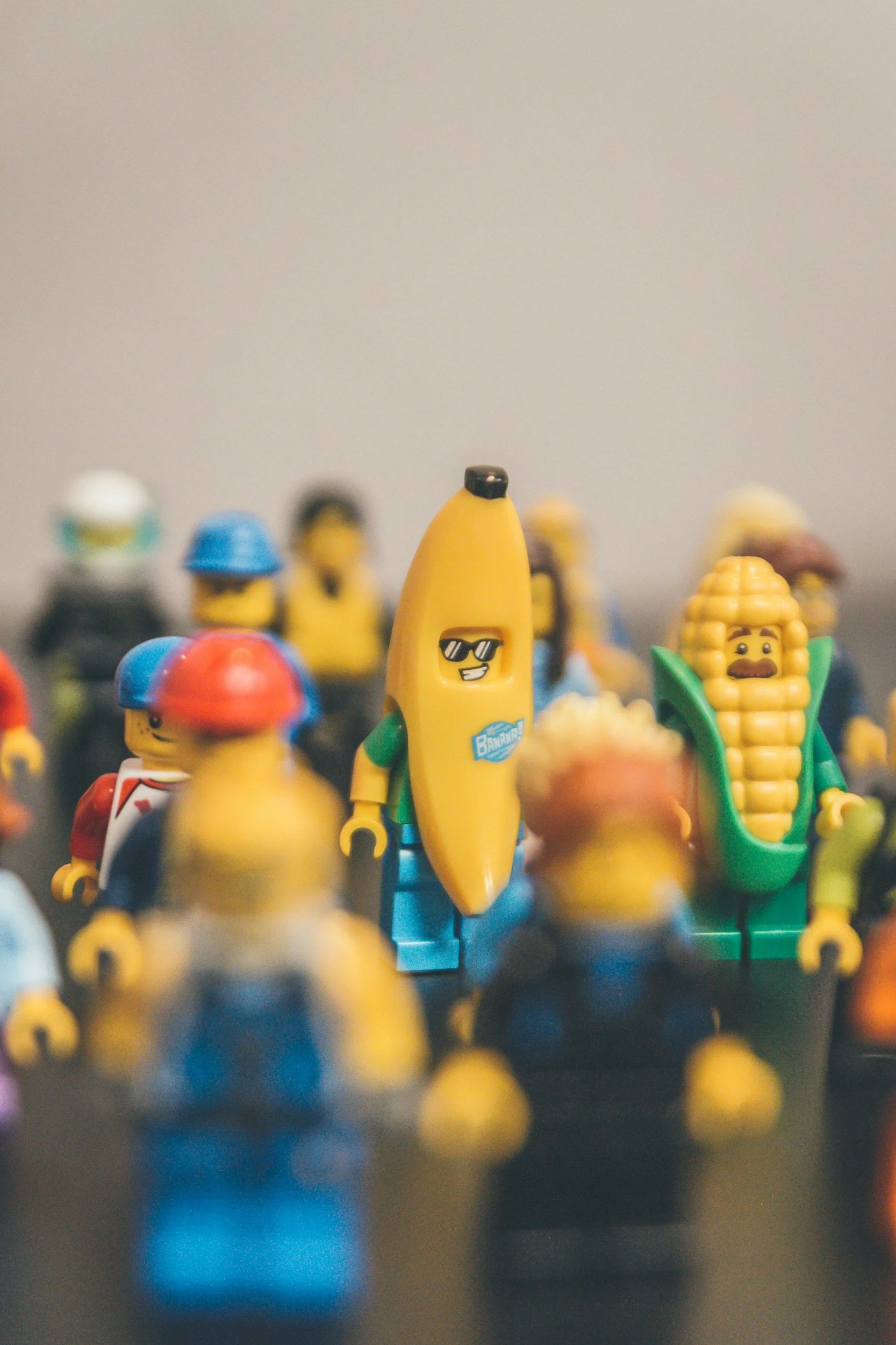 Blurred group of LEGO minifigures, featuring a banana character wearing sunglasses in the center and a green-suited character beside it