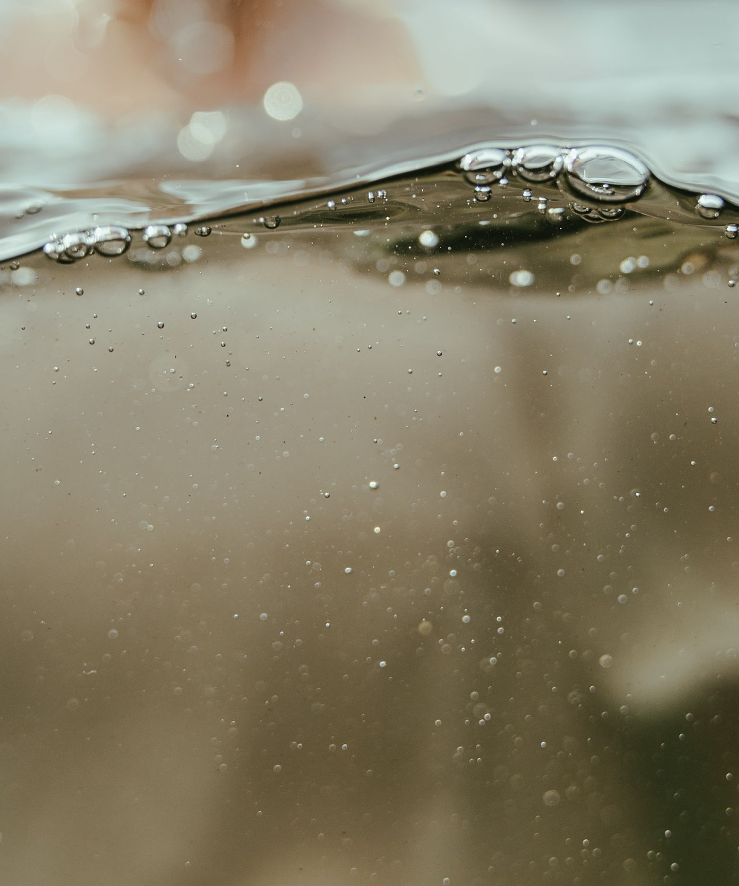 Macro close-up of bubbles rising beneath a reflective water surface