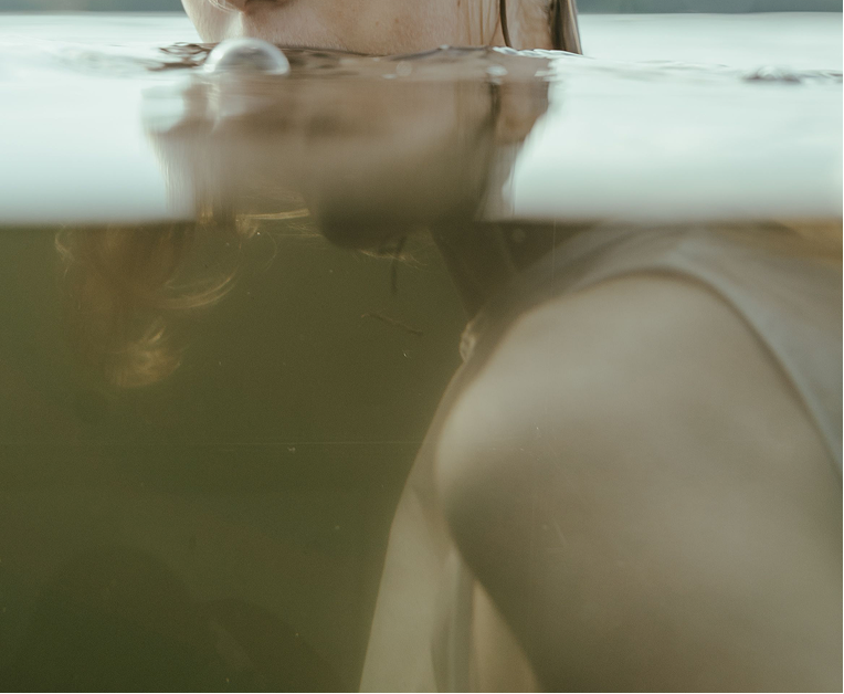 Artistic split underwater portrait of a woman partially submerged in a swimming pool