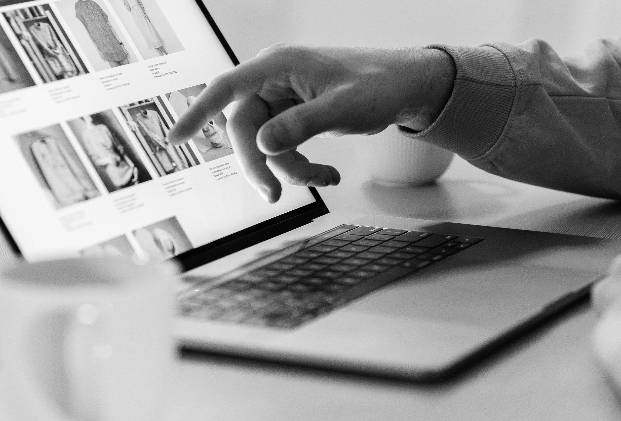 Black-and-white photograph of a person reviewing creative designs and visual layouts on a laptop.