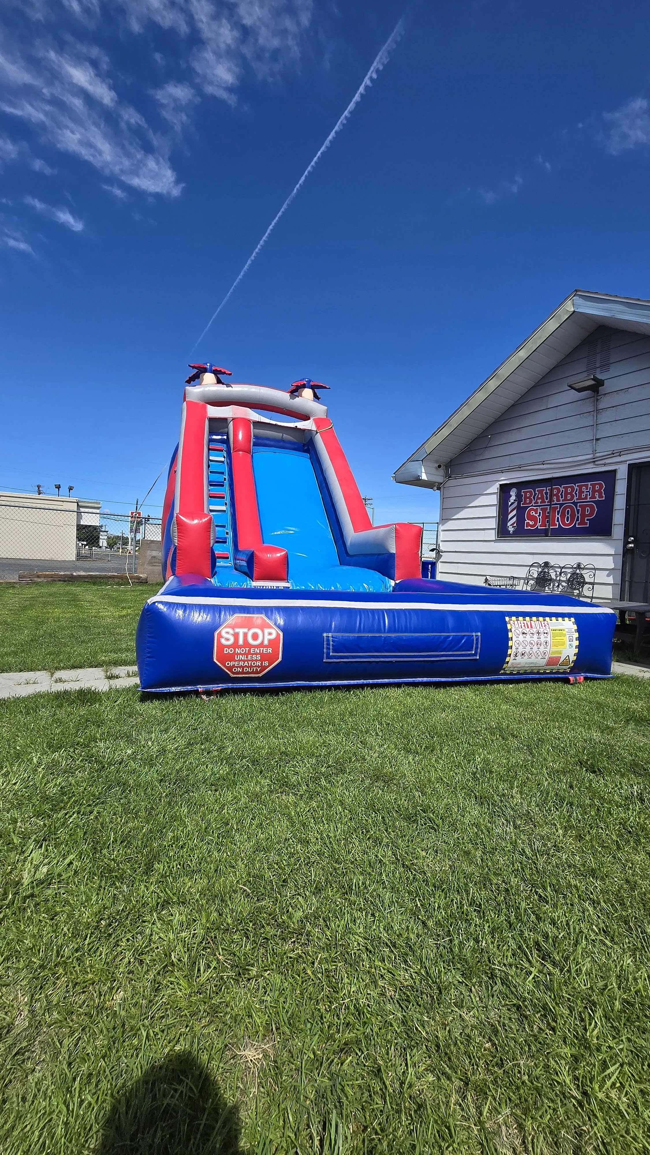 Red White N' Cool patriotic inflatable waterslide with red, white and blue sliding lanes and splash pool, set up on a grassy lawn for a summer party in the Tri-Cities.