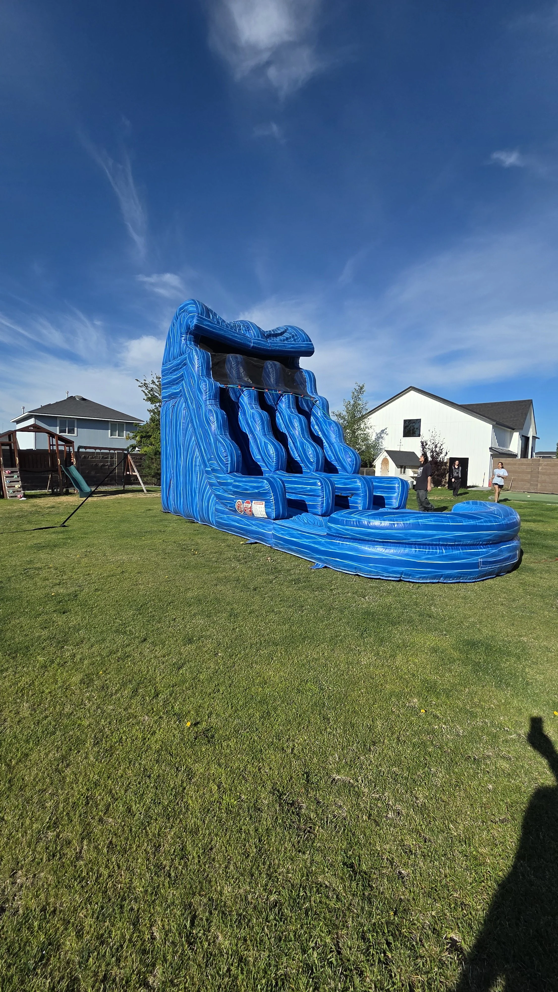 Large Double Trouble dual-lane inflatable waterslide set up on a grassy residential lawn for a backyard party rental in the Tri-Cities, WA.