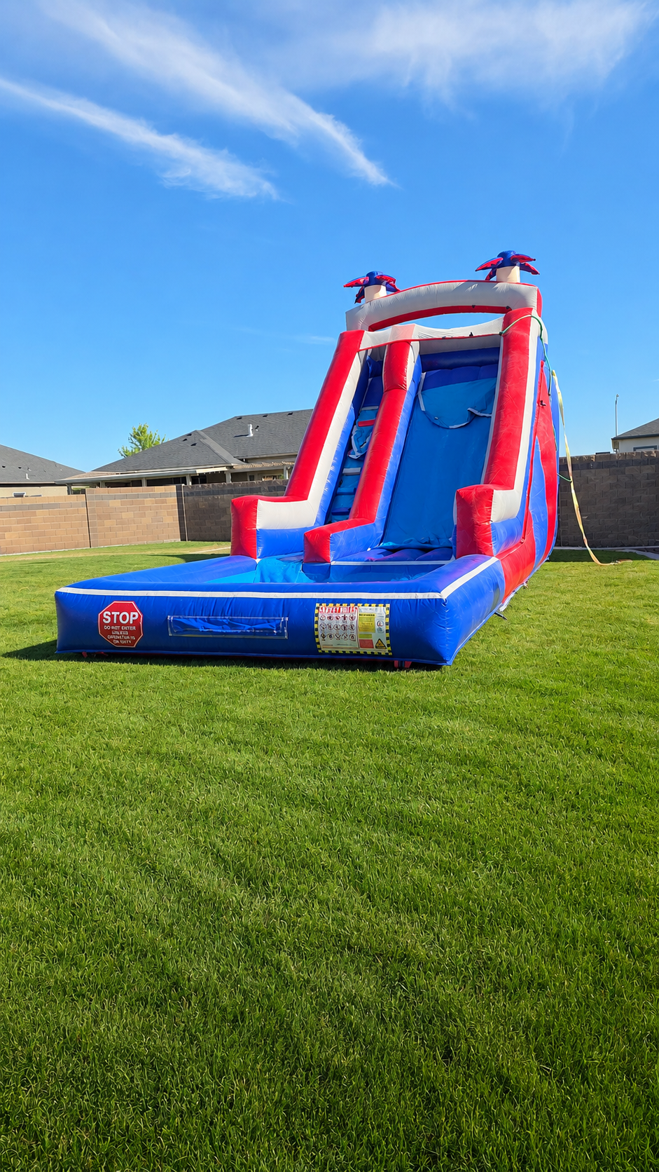 Red White N' Cool red, white and blue inflatable waterslide set up on a grassy lawn beneath a clear sky for a summer backyard party.