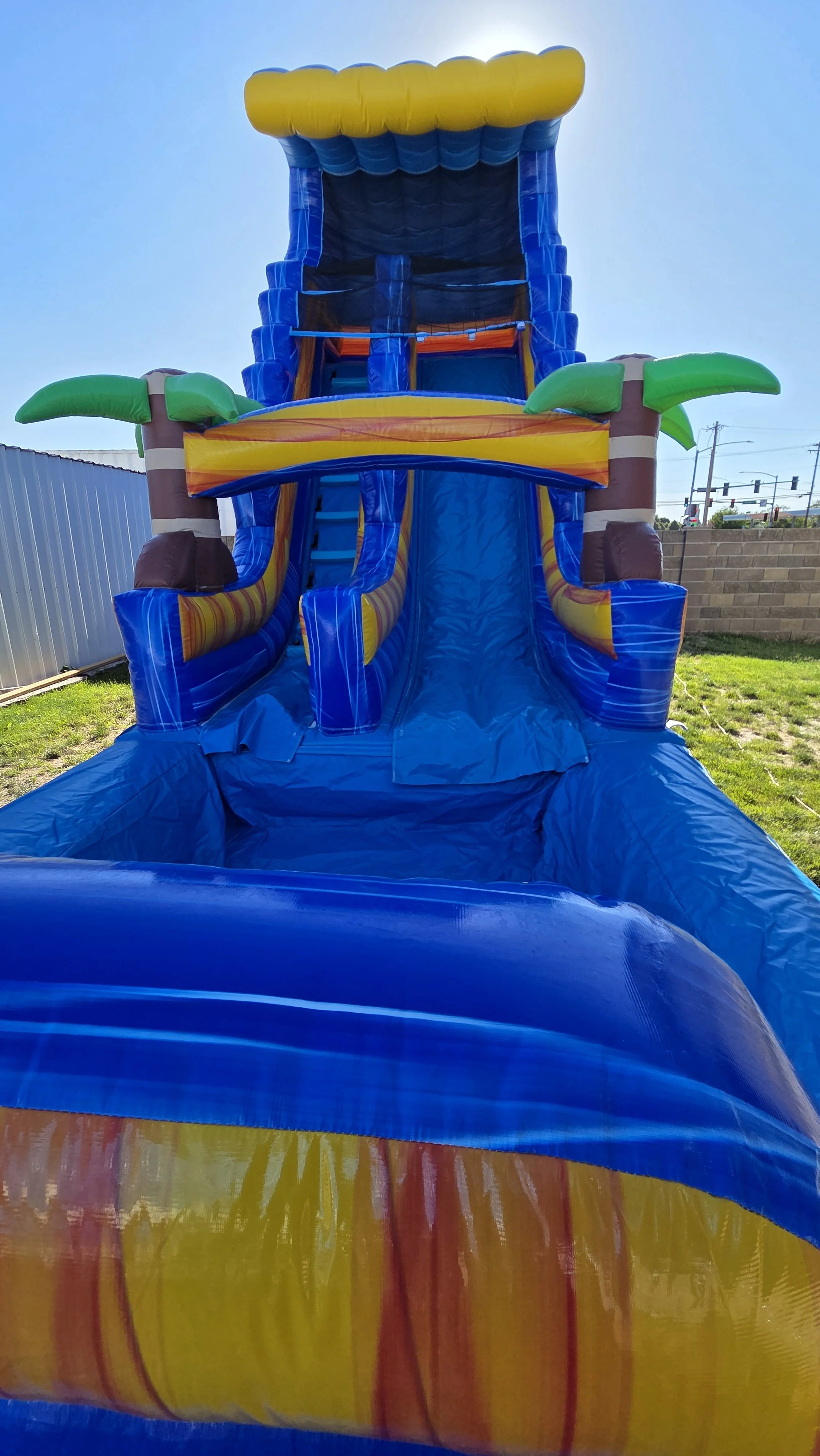 Side view of the Crazy Coconut tropical inflatable waterslide with palm-tree decorations, set up outdoors on a sunny day.