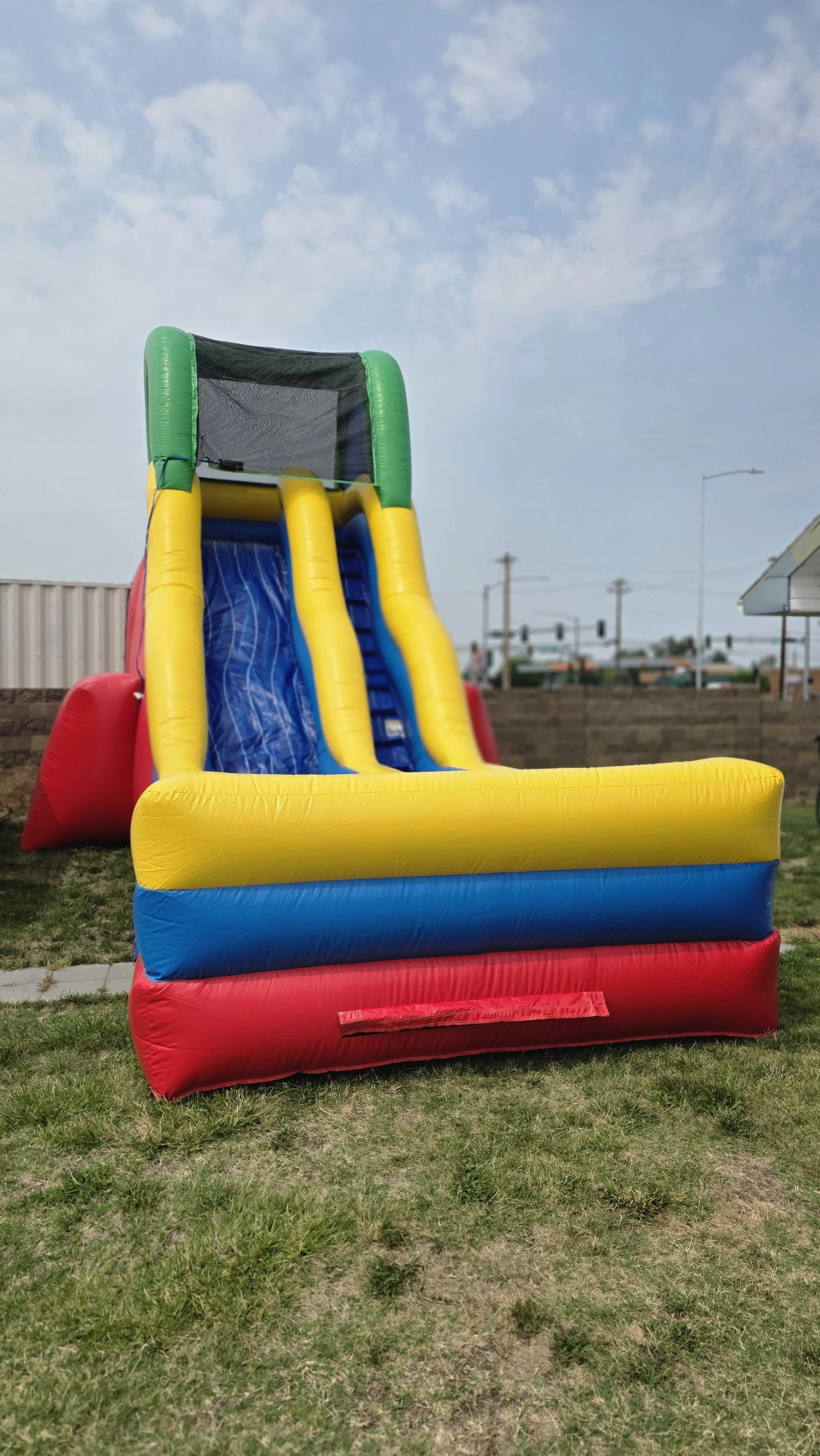 Front view of the Flip Flop inflatable waterslide with bright yellow and blue sliding sections beneath a partly cloudy sky.