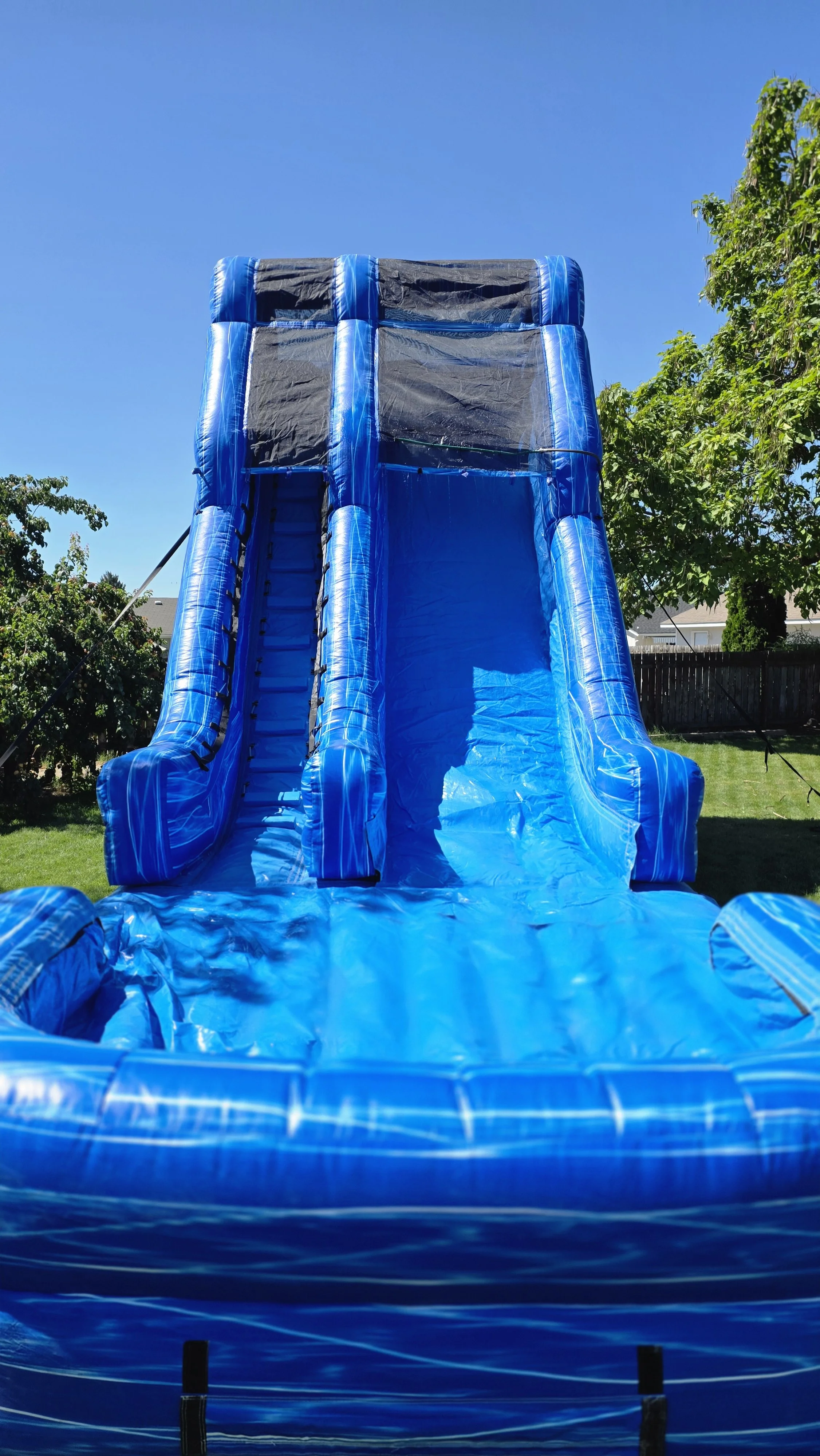 Front view of Big Blue's massive inflatable waterslide with two blue sliding lanes beneath a clear sky, offered by Waterslides Kennewick.