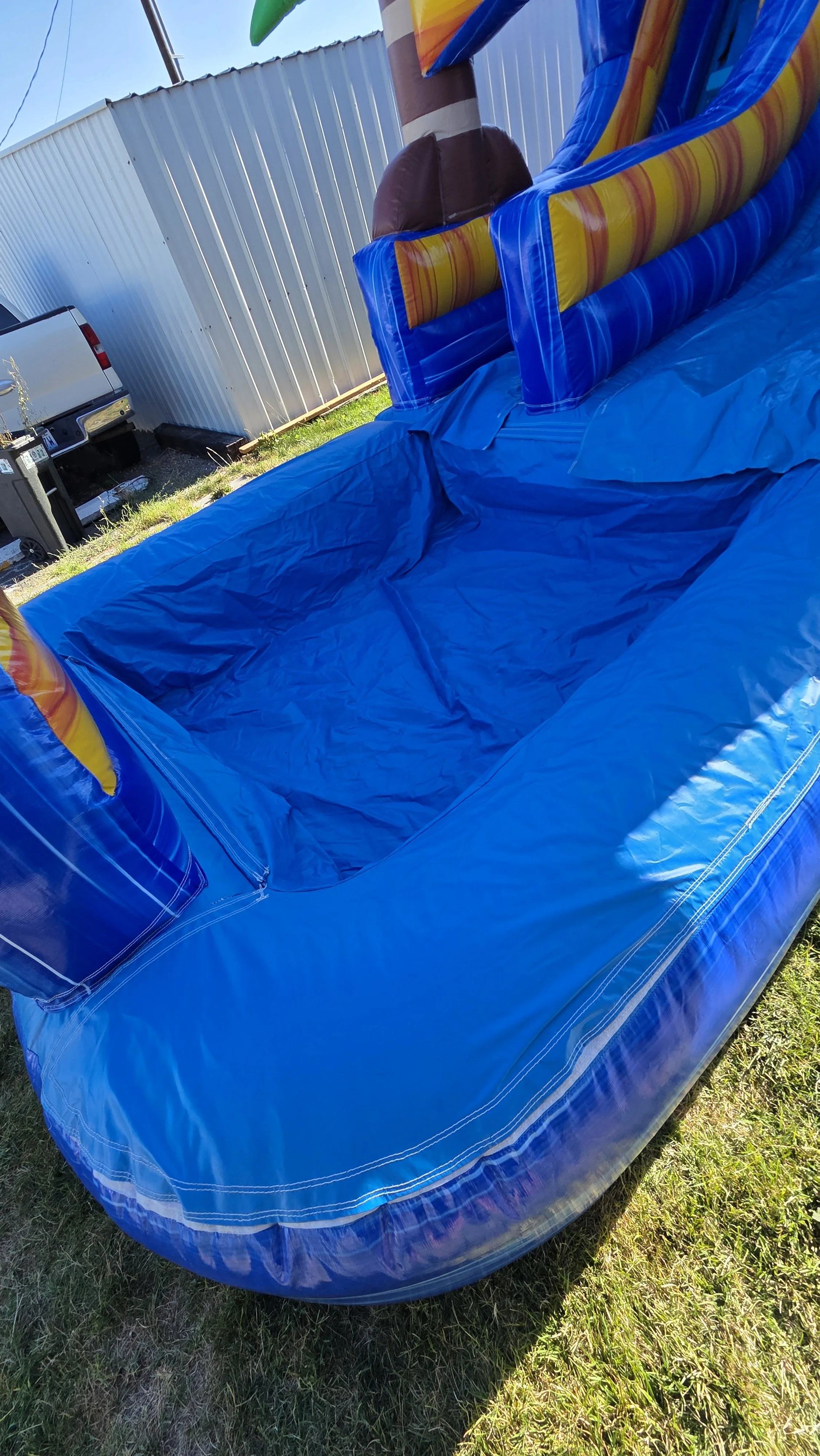 Crazy Coconut inflatable waterslide rental featuring blue, yellow and orange sections on a grassy lawn, serving Richland and the Tri-Cities, WA.