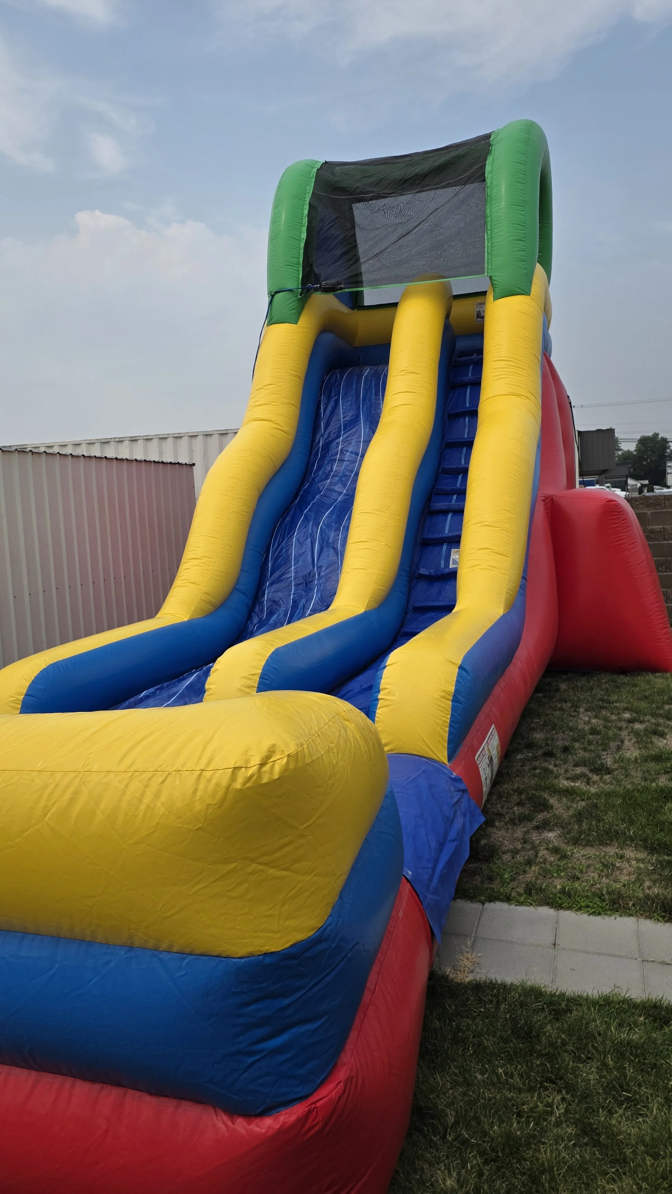 Rider's-eye view down the Flip Flop blue and yellow inflatable waterslide, overlooking the surrounding outdoor area.