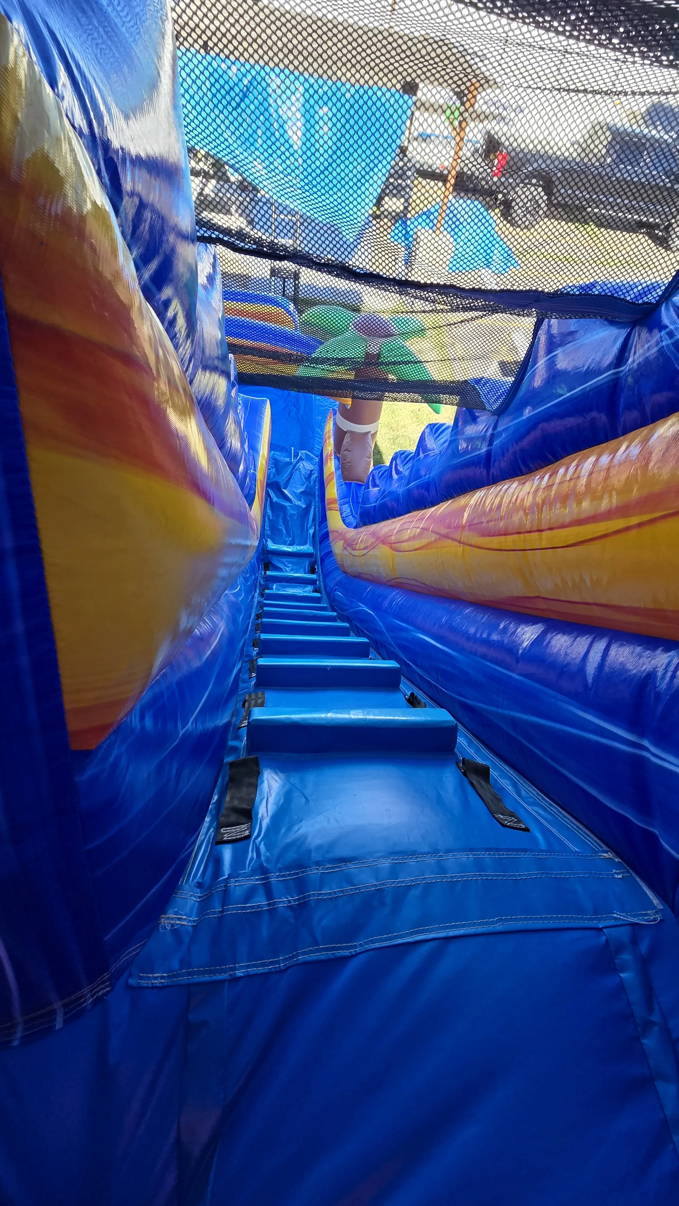 Inside view of the Crazy Coconut inflatable waterslide showing padded climbing steps and protective netting for riders.
