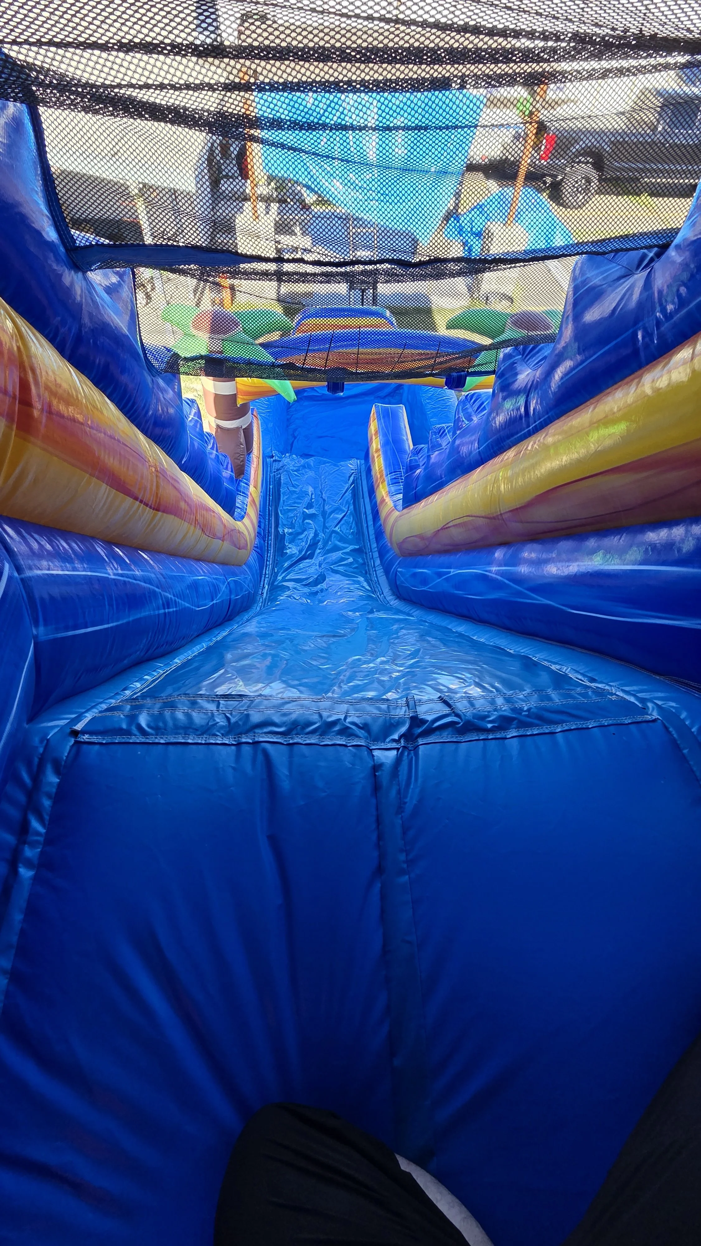 Interior view of the Crazy Coconut inflatable waterslide featuring a blue inflatable floor, colorful walls and protective safety netting.