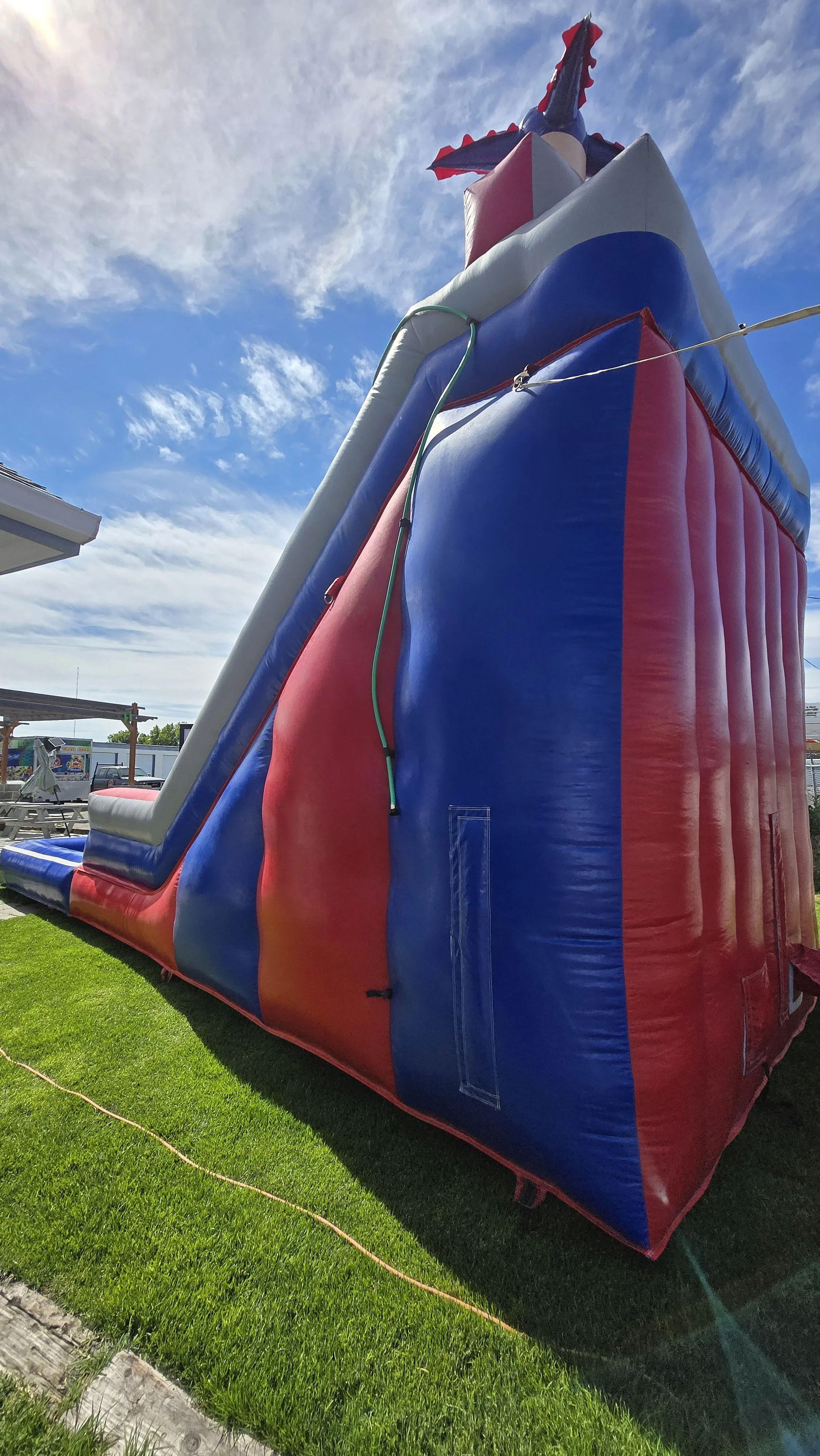 Side view of the Red White N' Cool red, white and blue inflatable waterslide with a splash pool, available from Waterslides Kennewick.