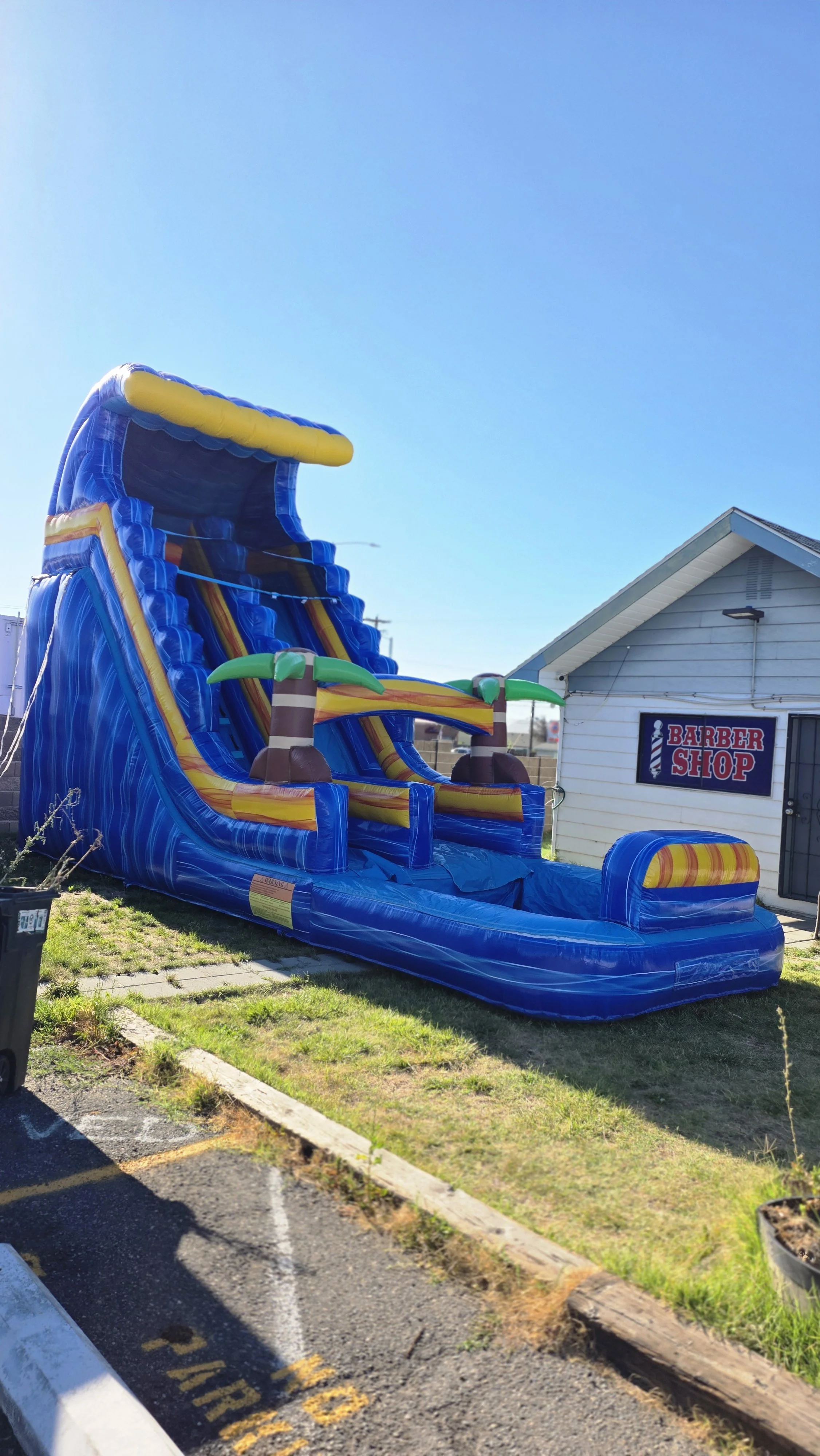 Side view of the Crazy Coconut tropical inflatable waterslide with palm-tree decorations, set up outdoors on a sunny day.