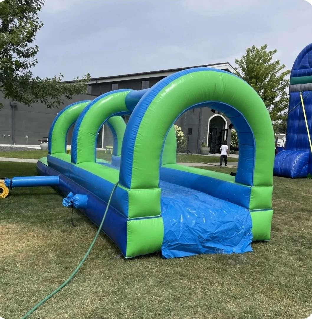 Side view of the 28-foot Slip Happens inflatable slip-and-slide with green arches and blue sliding lane, available for rental in Richland, WA.