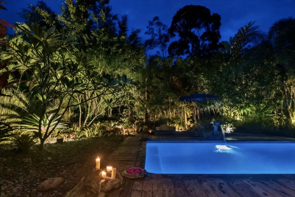 Casa Del Soul pool lit up at night beneath the jungle