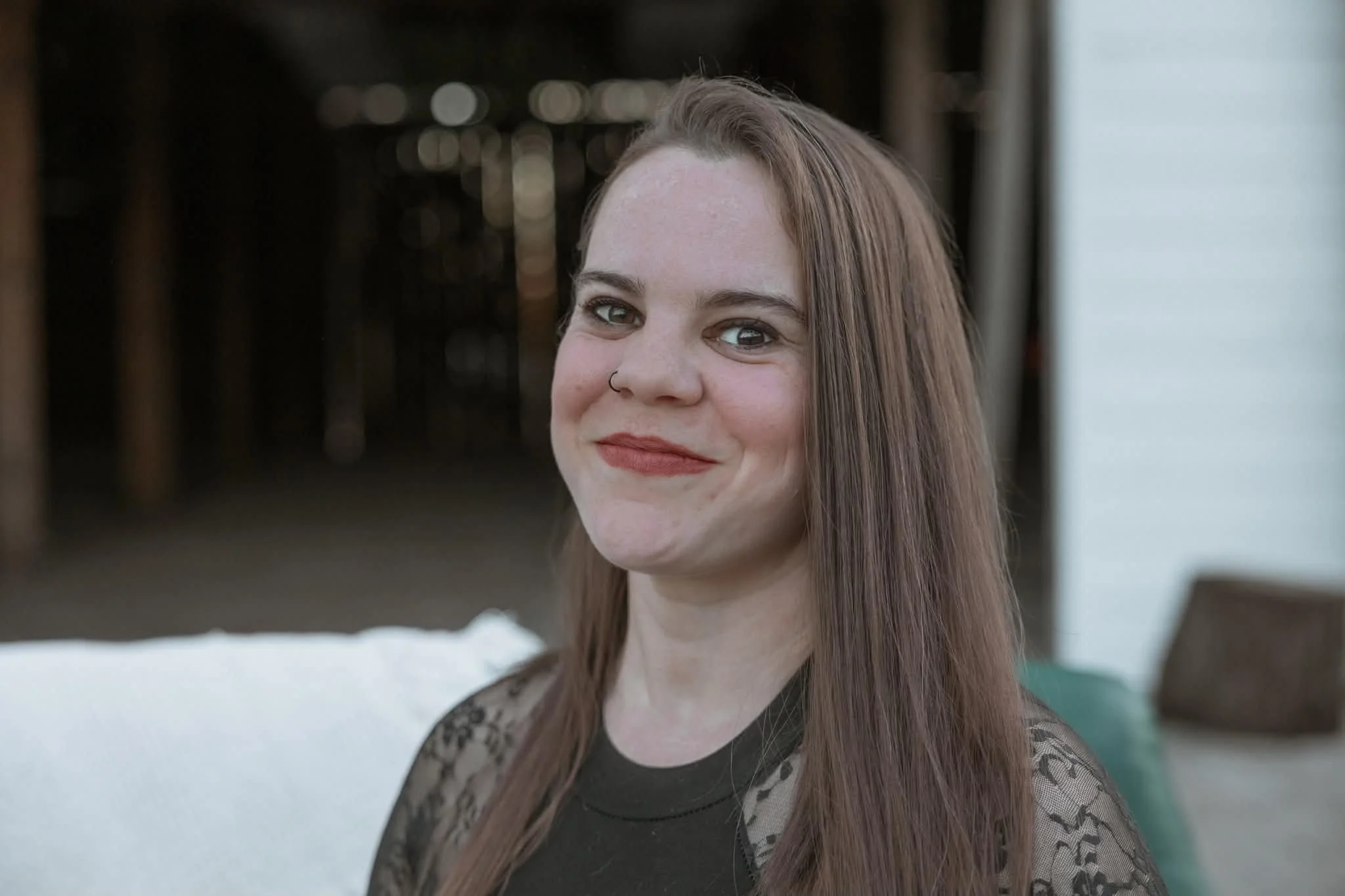 Smiling woman with long brown hair and a nose ring posing outdoors