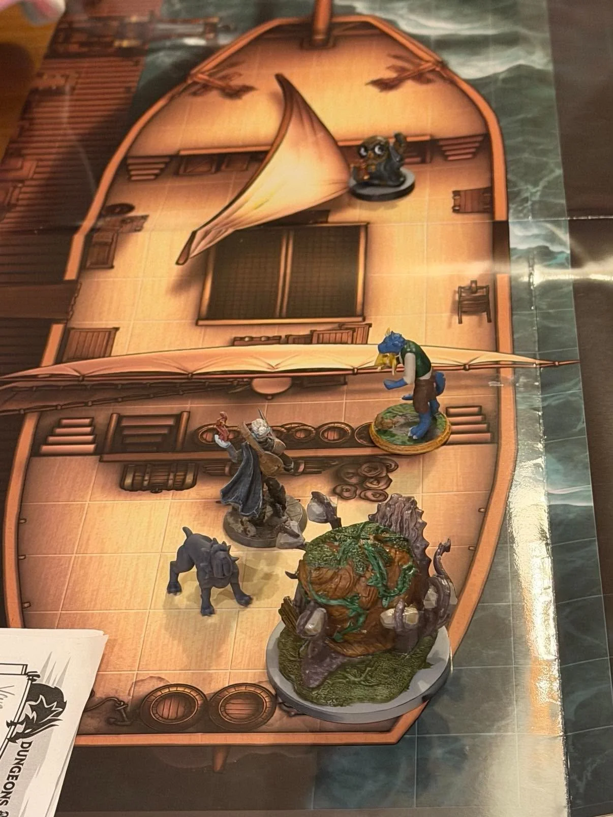 Tabletop role-playing game map with miniatures of fantasy characters and creatures arranged on it.