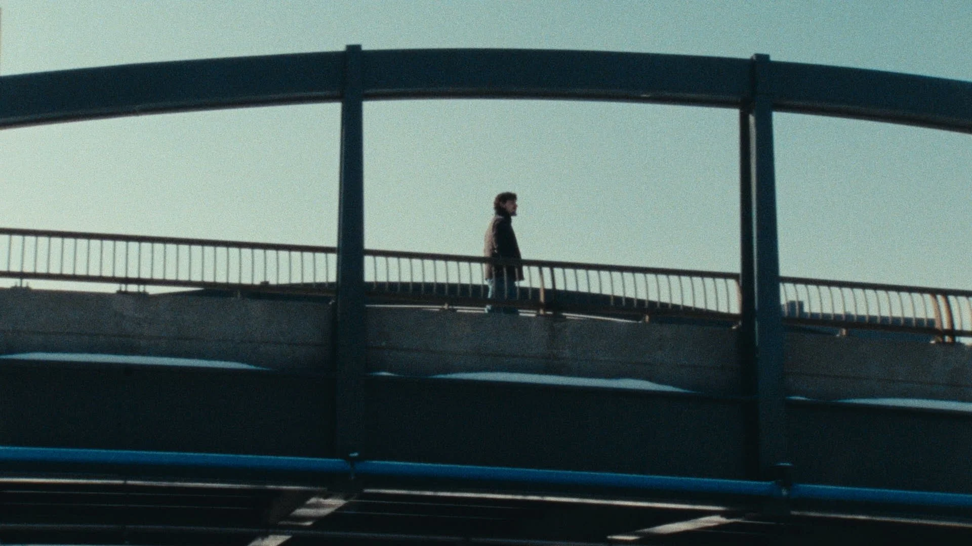 A person walking on a bridge with a clear sky background