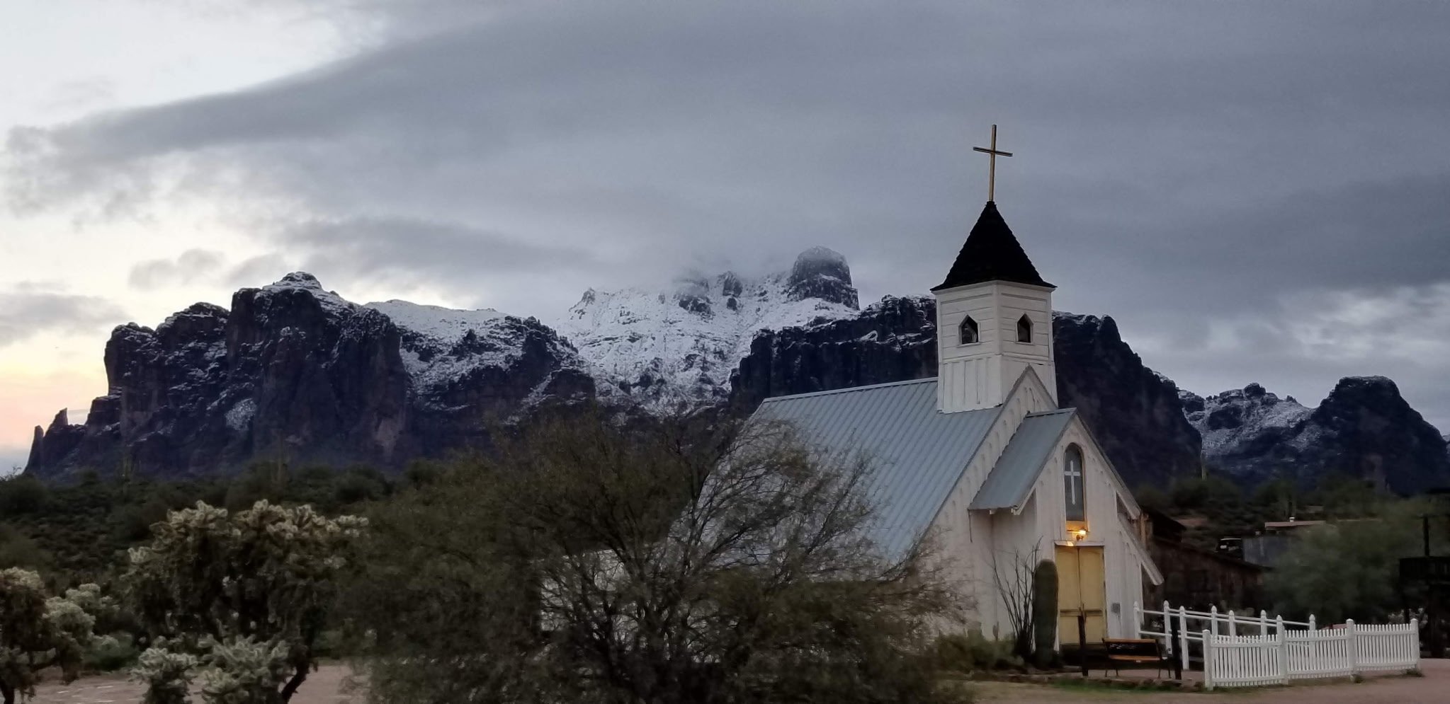 A small white chapel beneath the snow-dusted Superstition Mountains