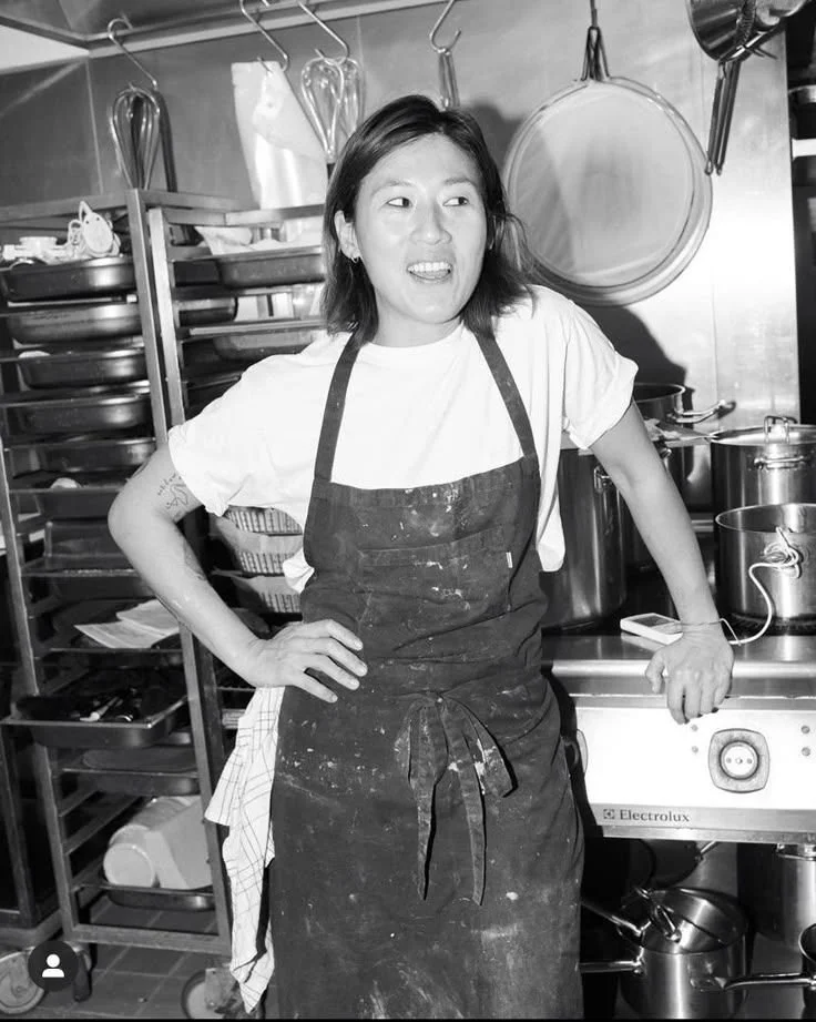 Black-and-white portrait of a smiling chef wearing an apron in a commercial kitchen