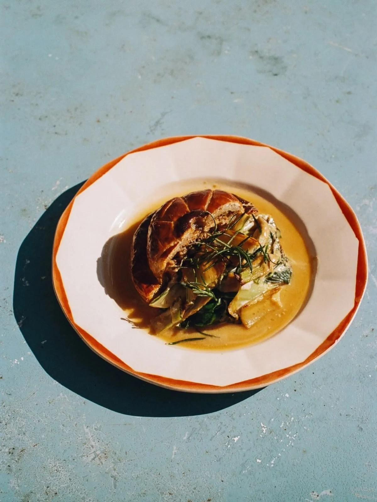 Roasted chicken with vegetables and herbs in a savory sauce on a white plate