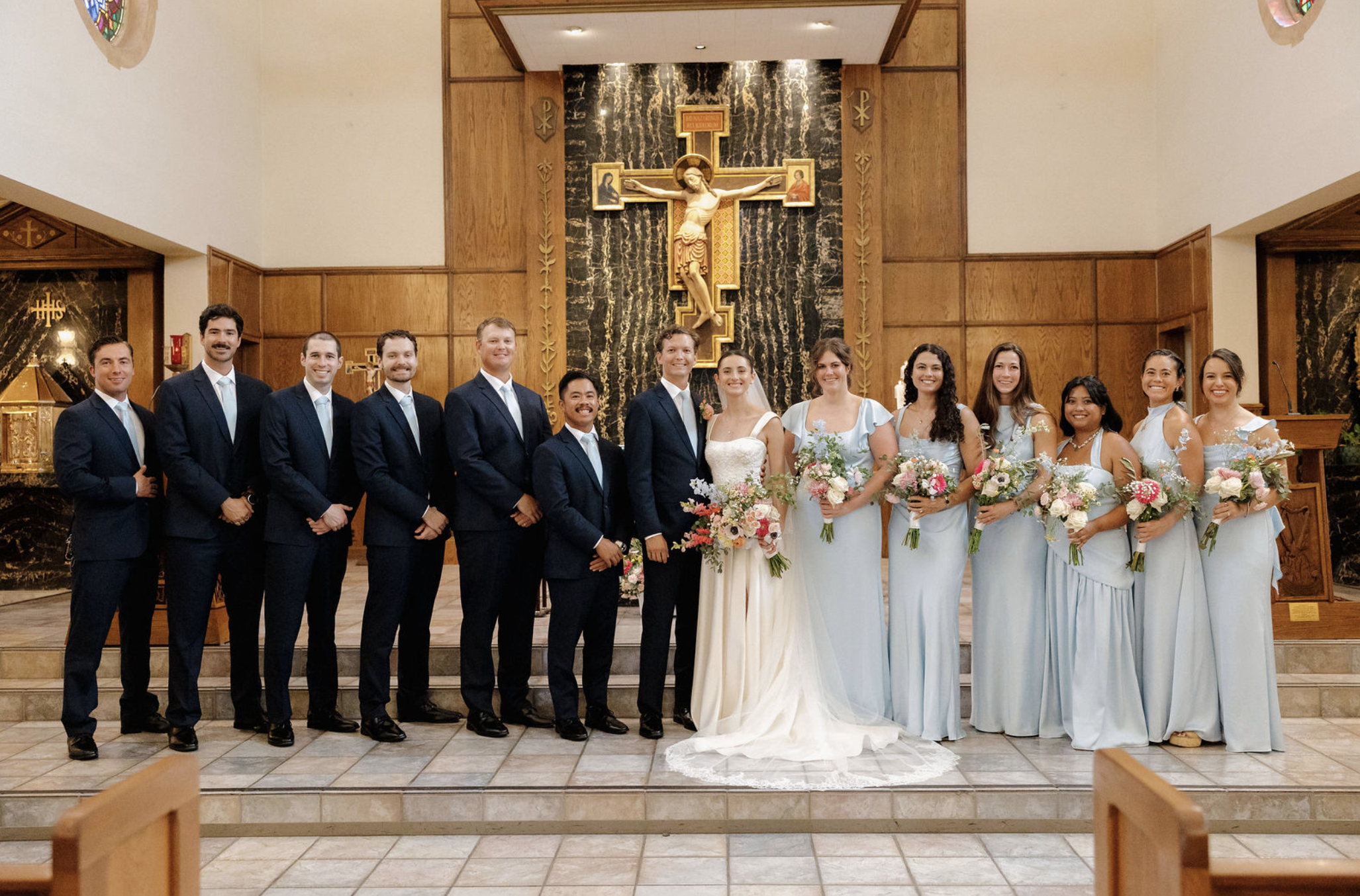 Beautiful bridal party and handsome groomsmen posing with newly weds at Saint Brigid Pacific Beach Parish. 
