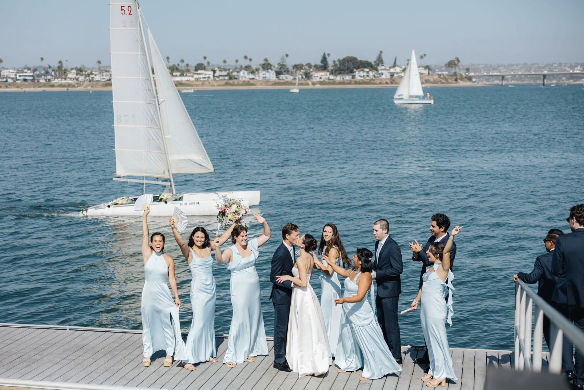 Beautiful bridal party and handsome groomsmen celebrating on docks of Mission Bay Yacht Club.