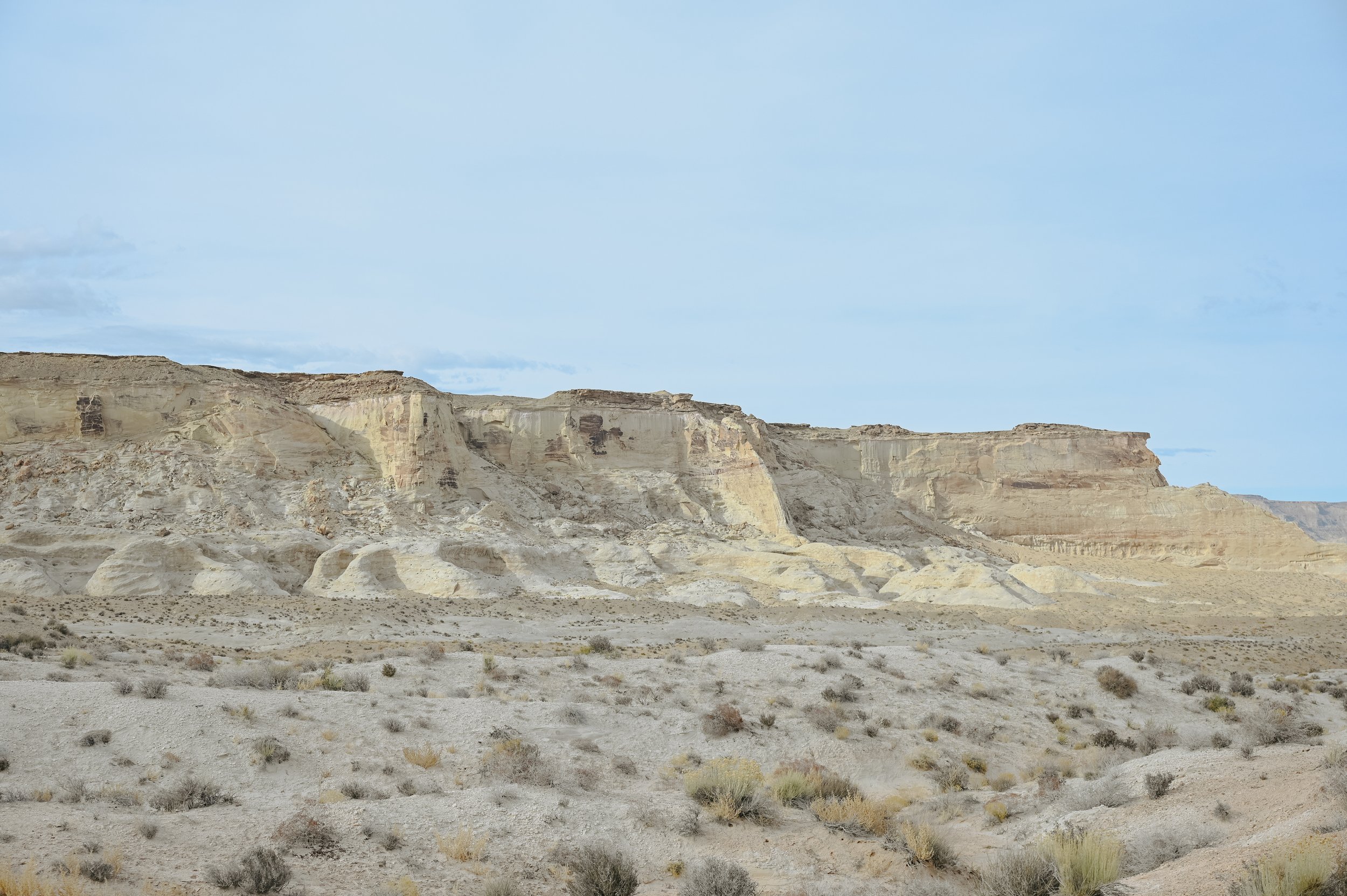 Layered pale desert cliffs above open scrubland.