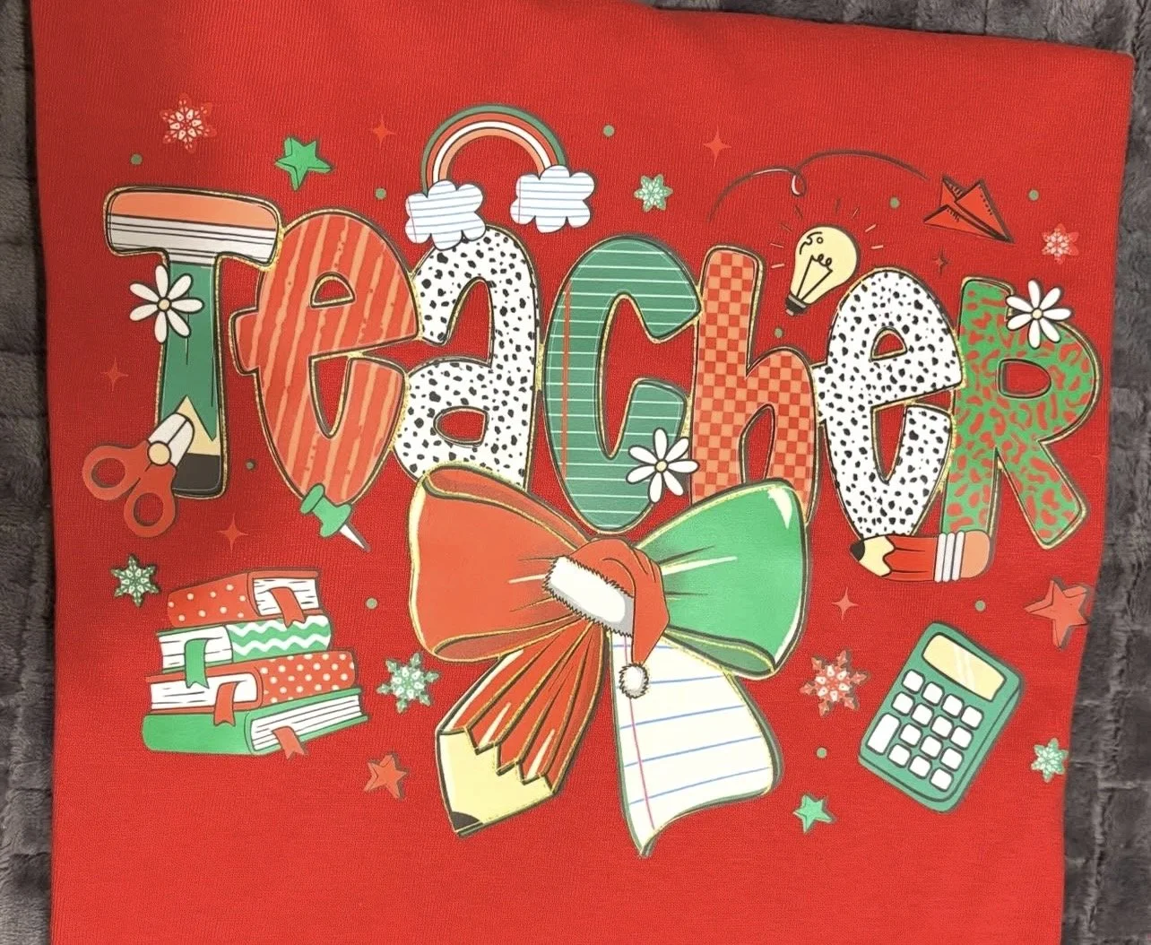 Colorful red Christmas advent calendar design with festive lettering, rainbow, ornaments, wrapped gifts, bow, pencil, books, calculator, scissors, light bulb, and snowflakes