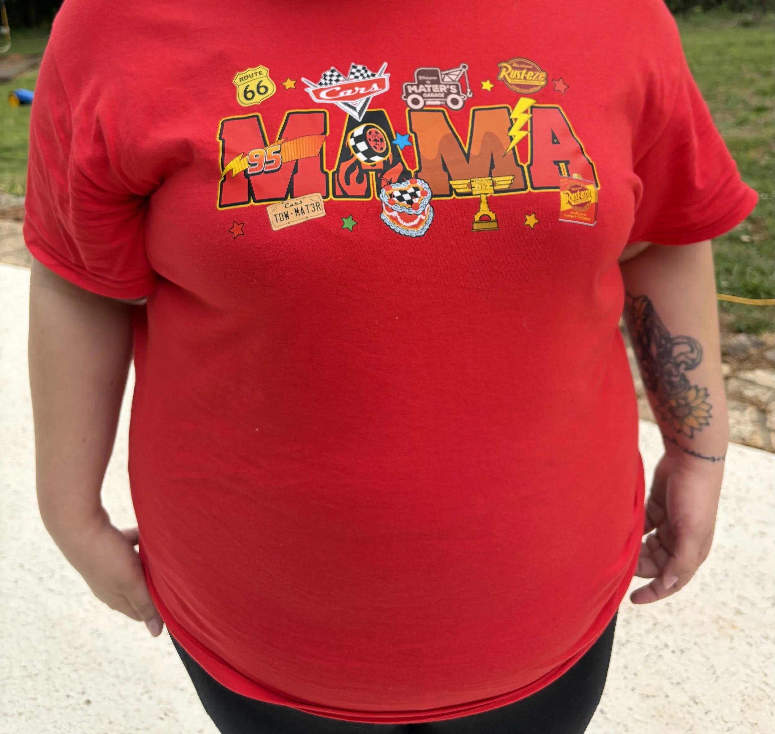 Person wearing a red Disney Cars-themed T-shirt featuring Lightning McQueen, Route 66, Mater, Rust-eze, and racing graphics.
