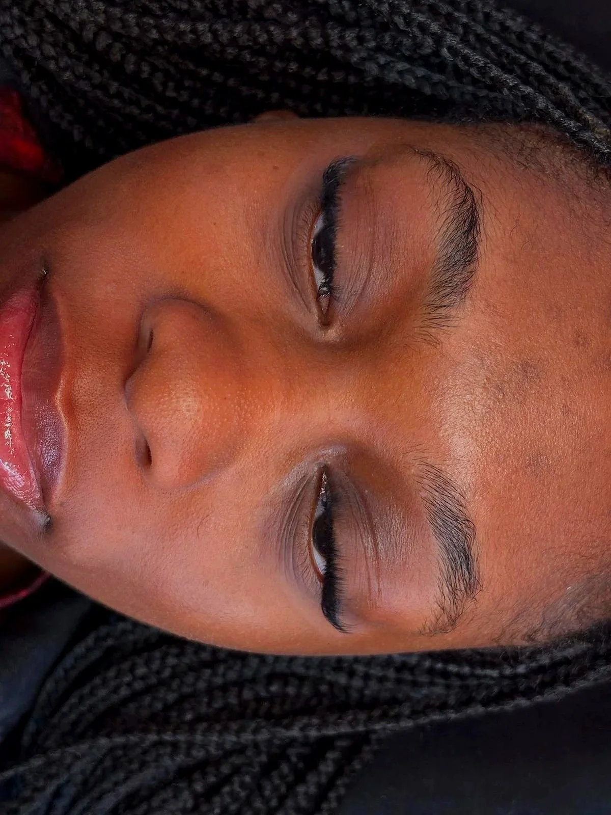 Close-up portrait of a Black woman with braided hair and long eyelashes