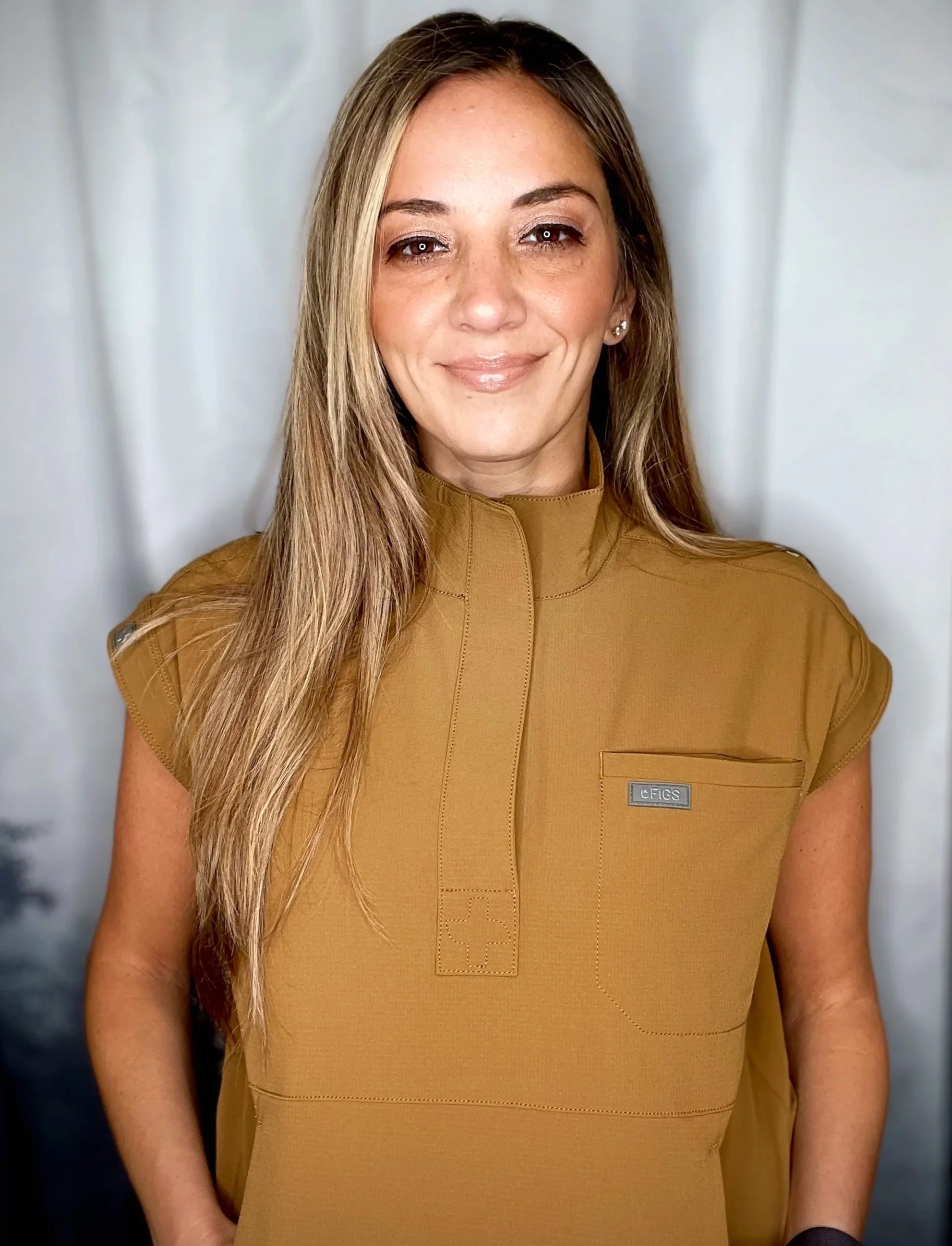 Melanie Boling with long blonde hair wearing a tan FIGS medical scrub top