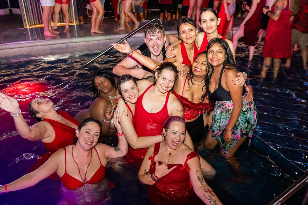 Women dressed in red cheering together in a pool at night