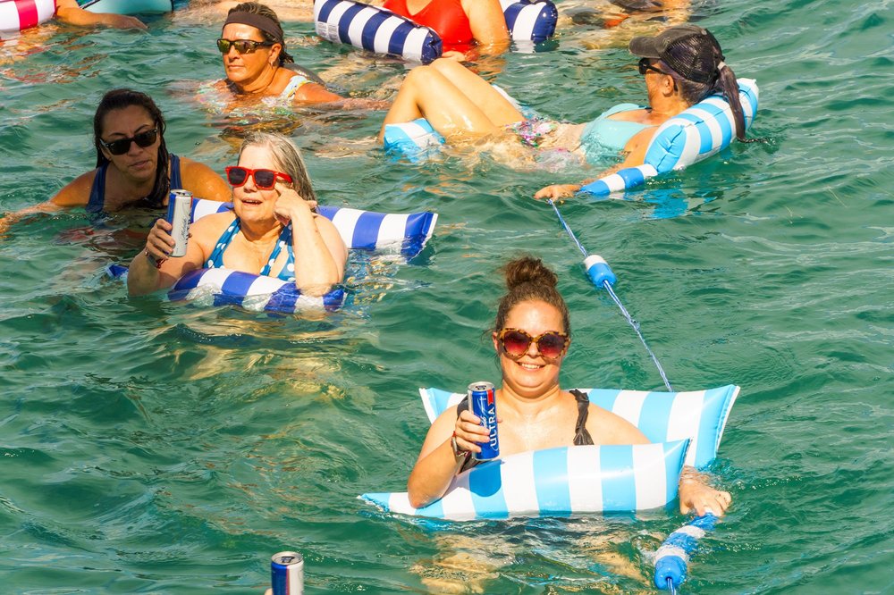 Women floating on striped floats in clear turquoise water