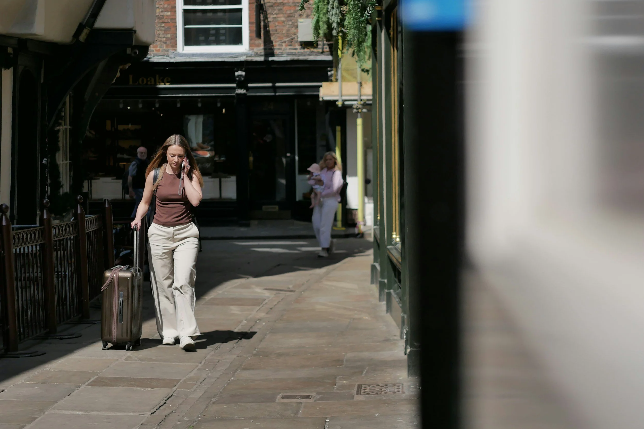 A traveler pulling a rolling suitcase down a narrow city street