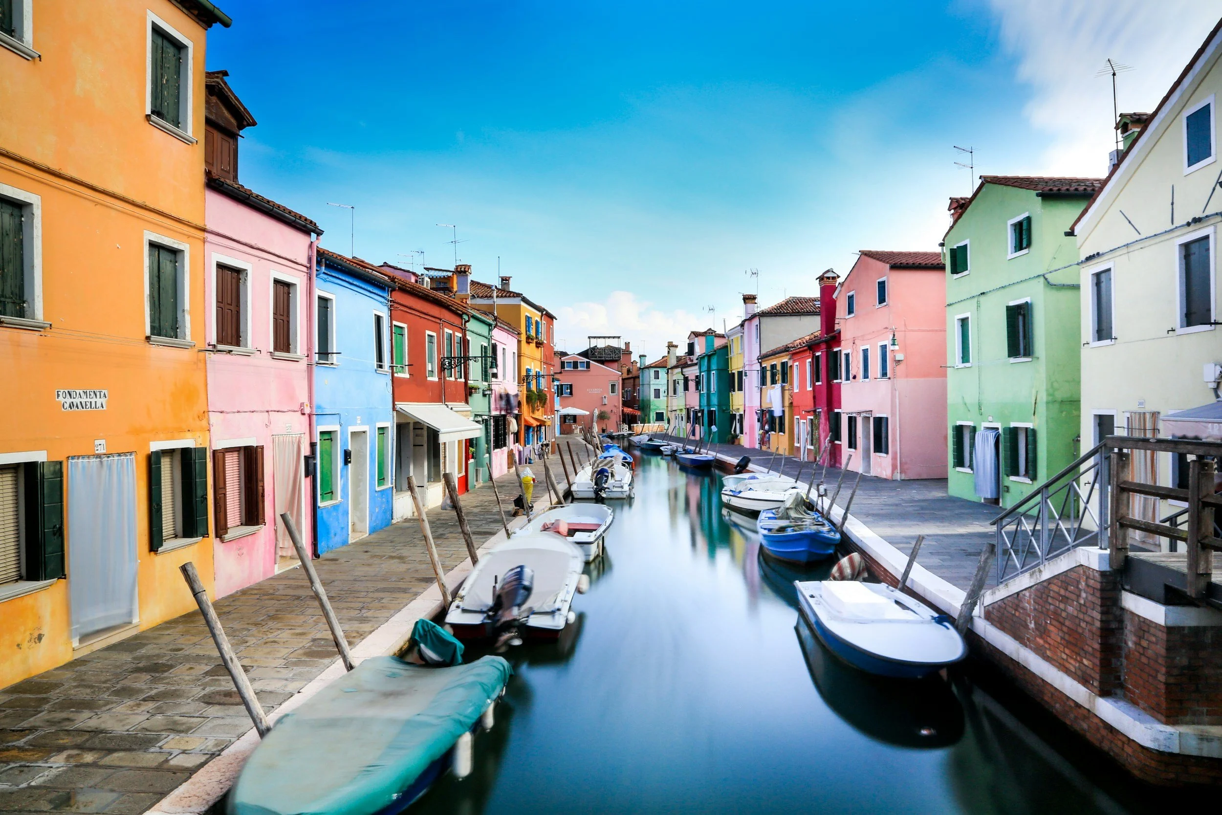 Brightly painted houses and moored boats along a canal on the island of Burano in the Venetian lagoon