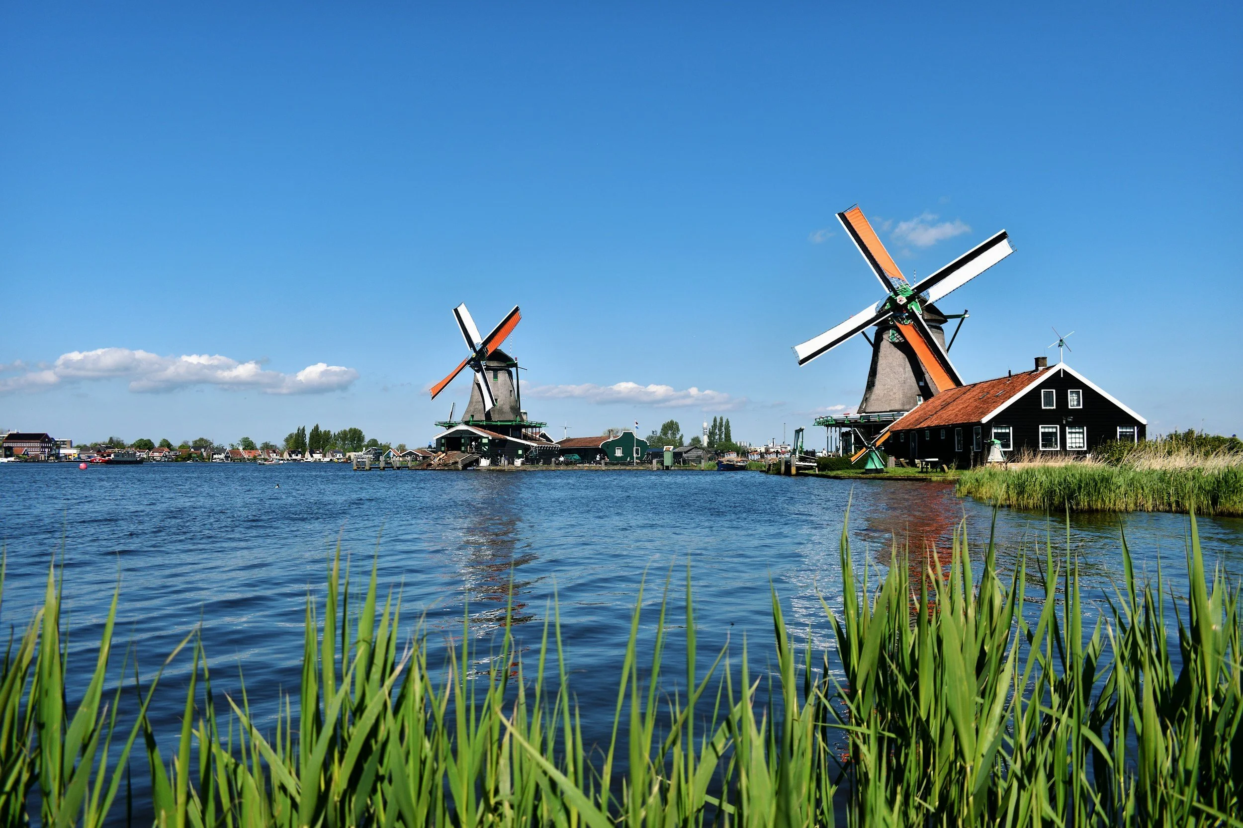 Historic windmills and a wooden house beside the water at Zaanse Schans in the Netherlands