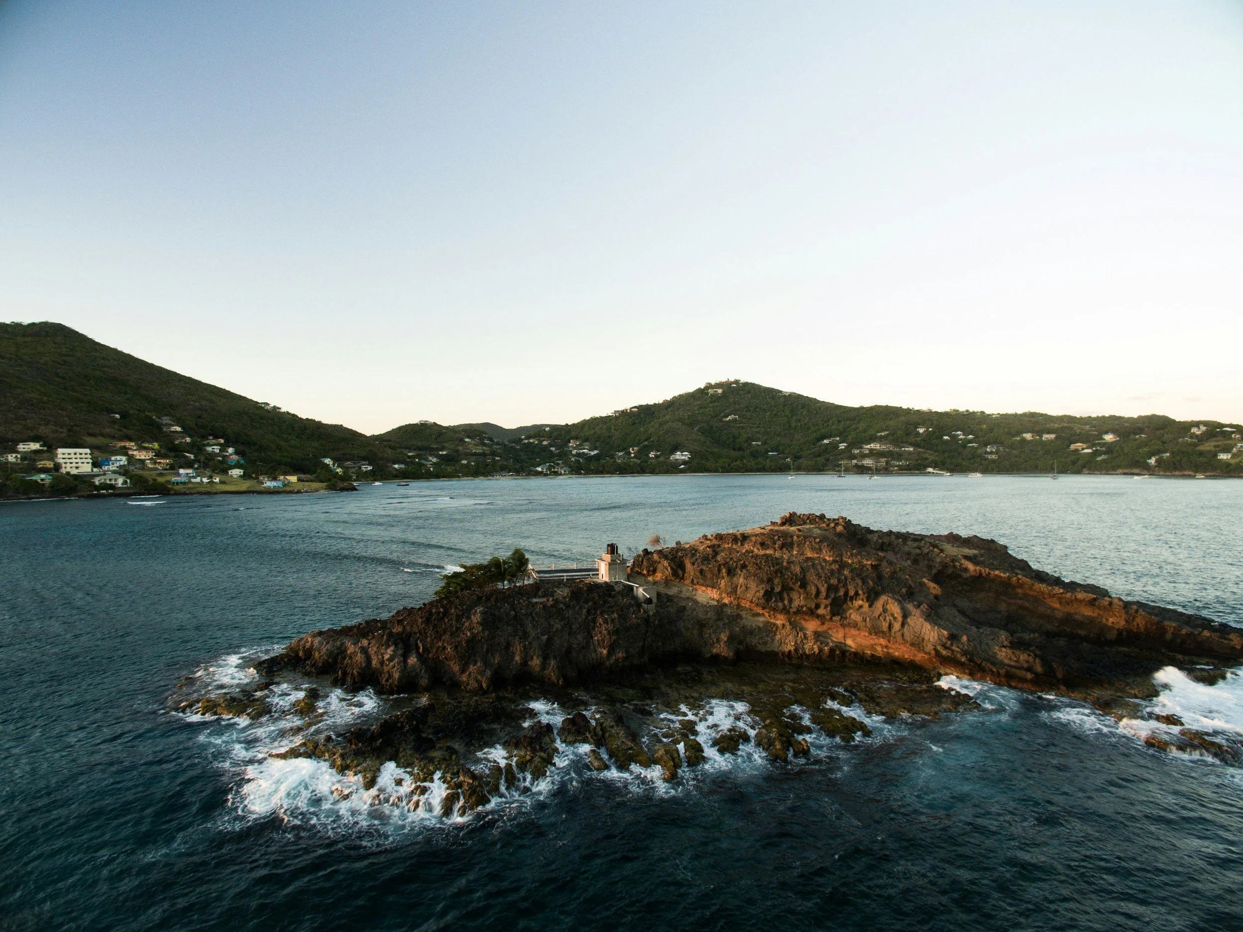 A rocky headland and green hills along the coast of Bequia in the Grenadines