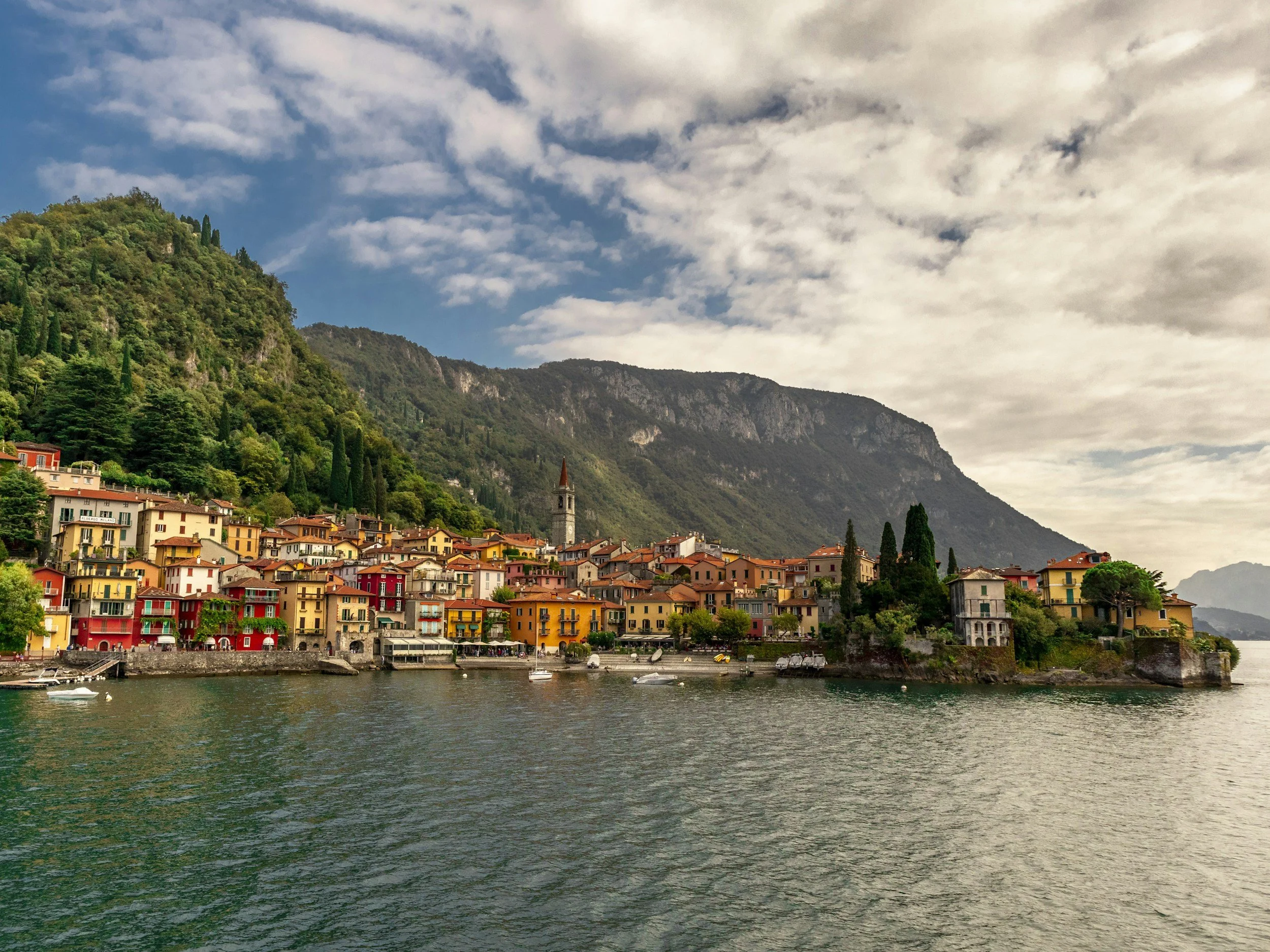 Colorful lakeside village on Lake Como with green mountains rising behind it
