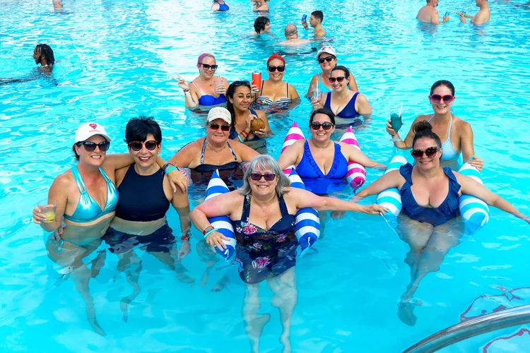 Women in swimsuits laughing together on striped pool floats