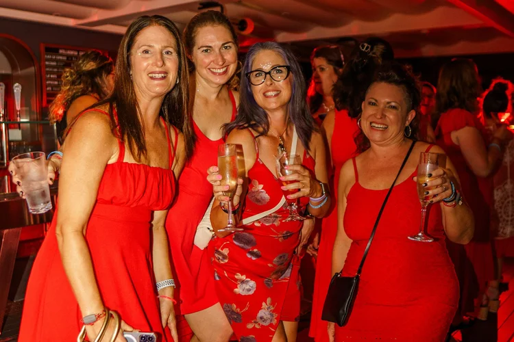 Women dressed in red raising glasses
