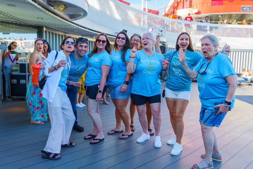 Women in matching blue T-shirts posing together on a ship's deck