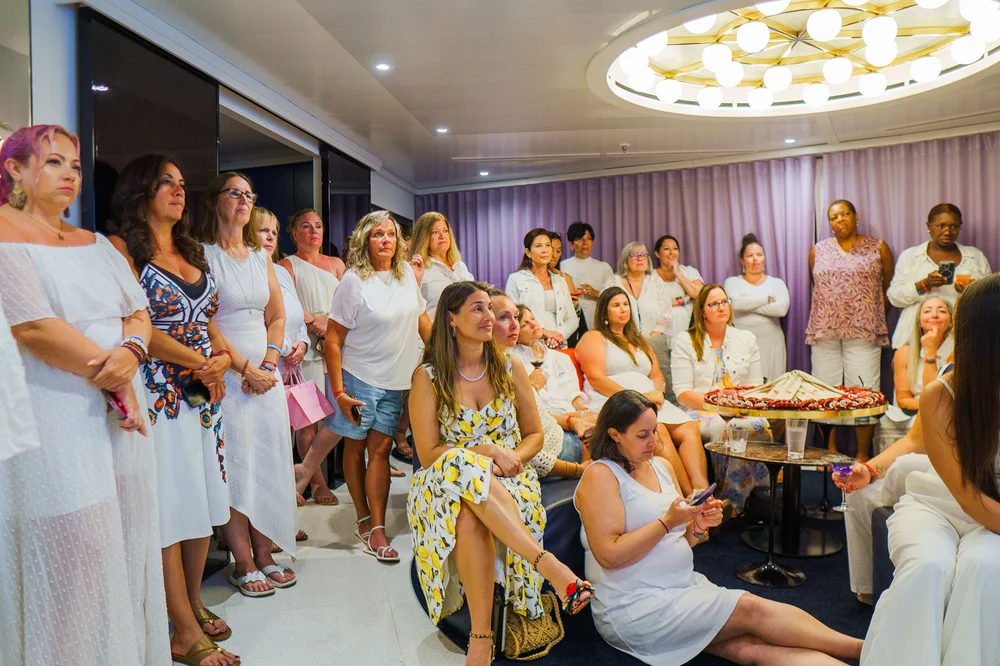 A room full of women dressed in white gathered for an event on board