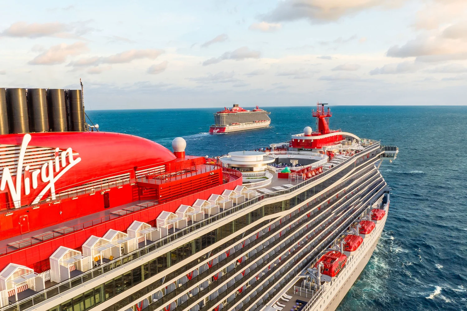Two red-and-white Virgin Voyages ships at sea