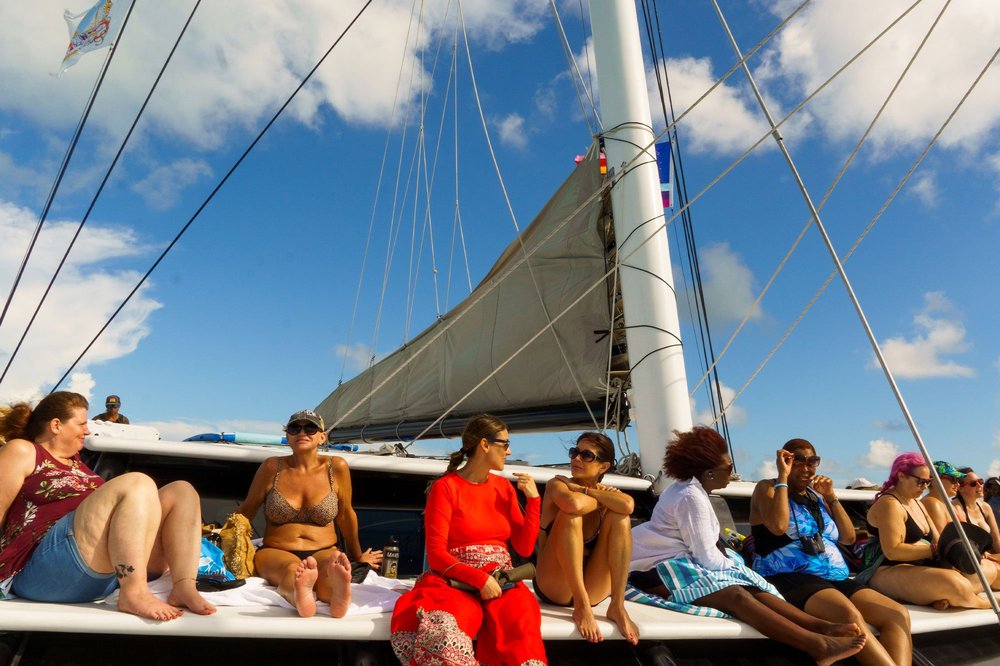 Women relaxing on the deck of a sailing catamaran under a blue sky