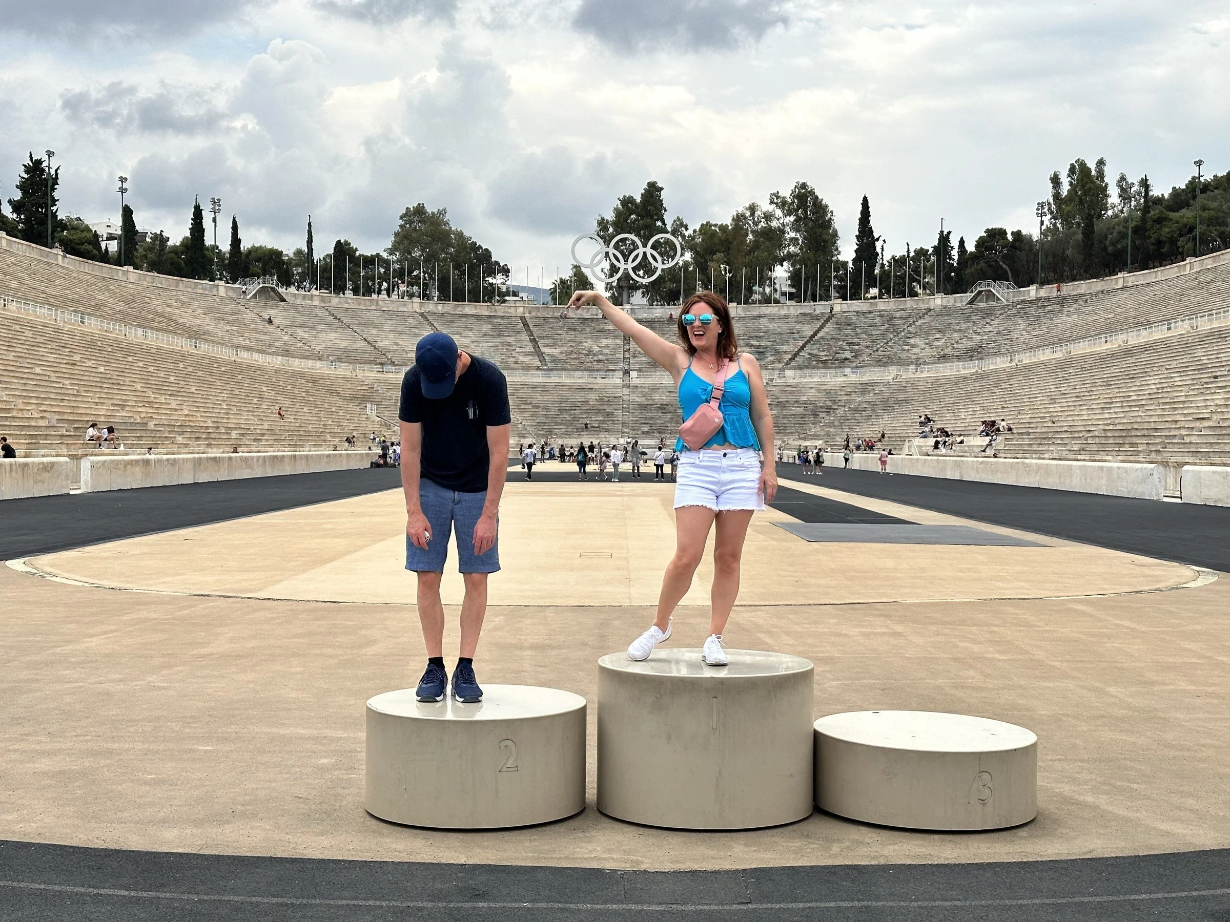 Samantha celebrating on the top step of the winners' podium in the marble Panathenaic Stadium in Athens, with a friend bowing on second place