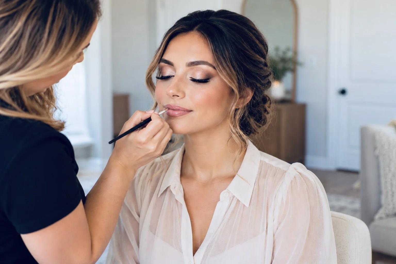 Makeup artist applying lip color to a bride with an elegant updo
