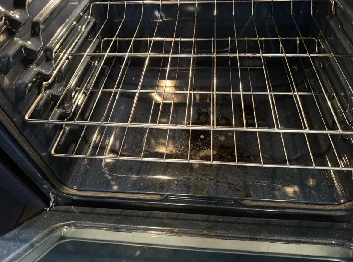 Open oven interior with two metal racks and food residue on the bottom.